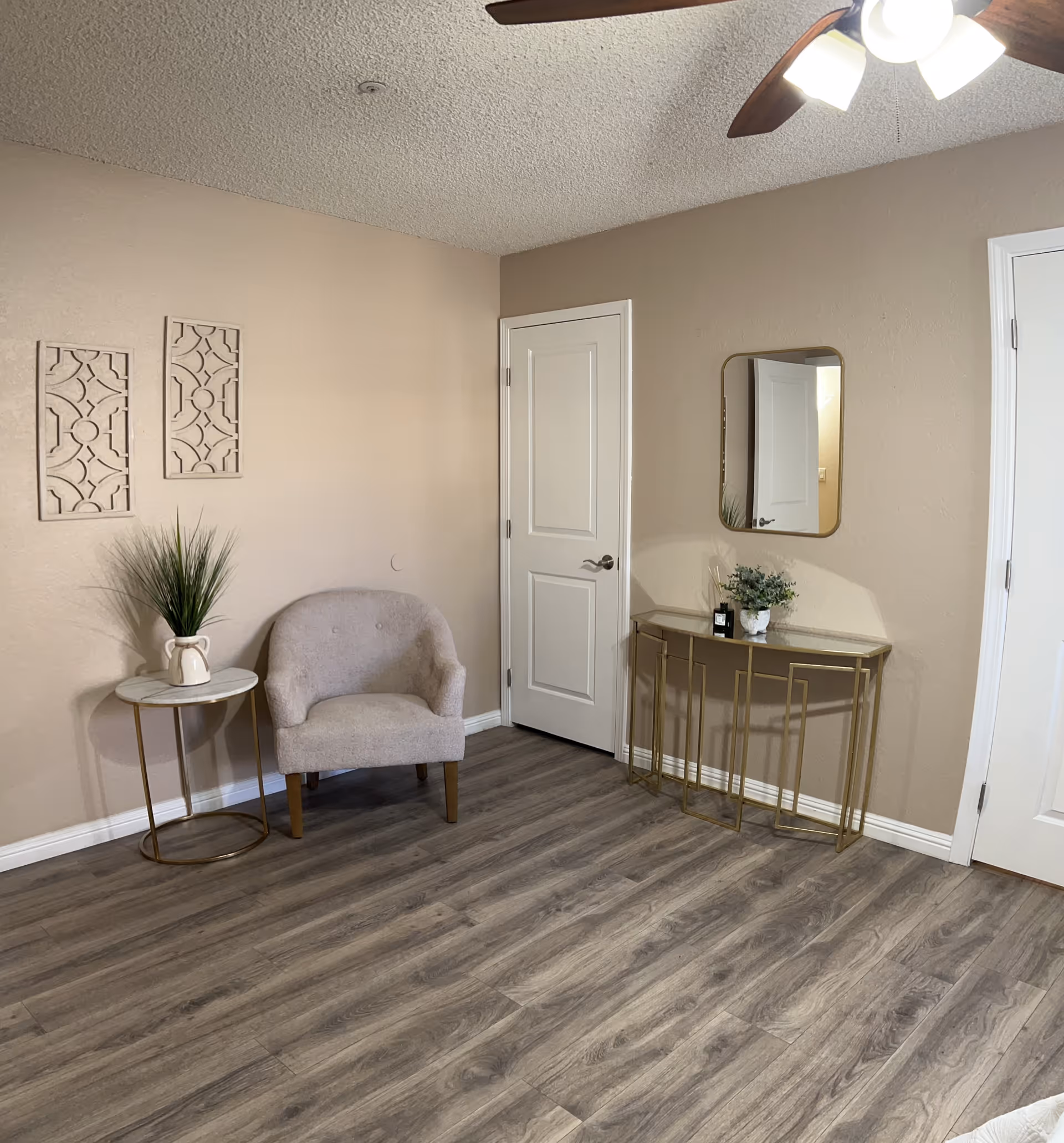 Neutral living area corner with beige walls, a plush chair, side table, and console desk.