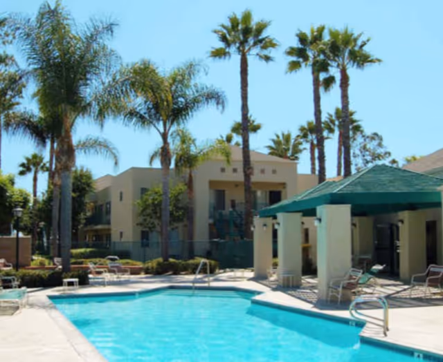 Outdoor pool area with palm trees and lounge chairs at Whispering Fountains.