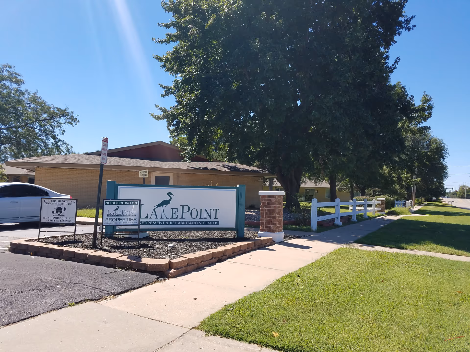 Exterior view of LakePoint Retirement and Rehabilitation Center with sign, lawn, and sidewalk.