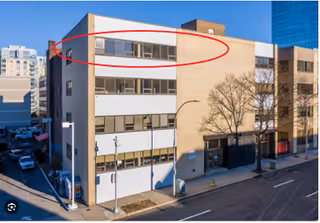Exterior view of a beige multi-story building on a city street.