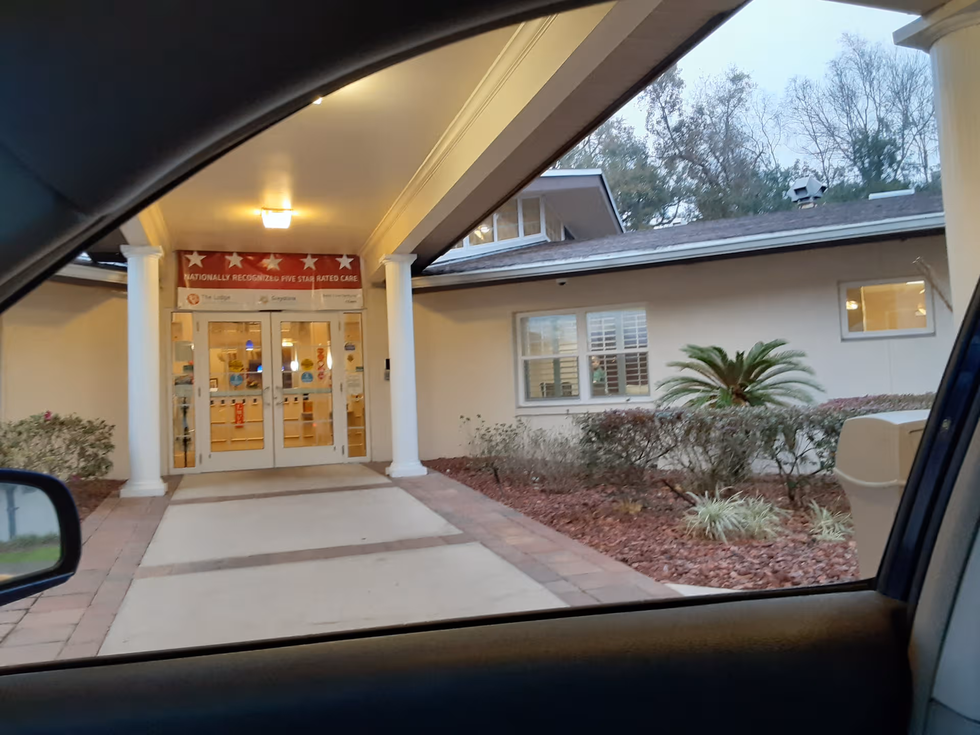 Front entrance of The Lodge Health & Rehabilitation Center under a covered driveway