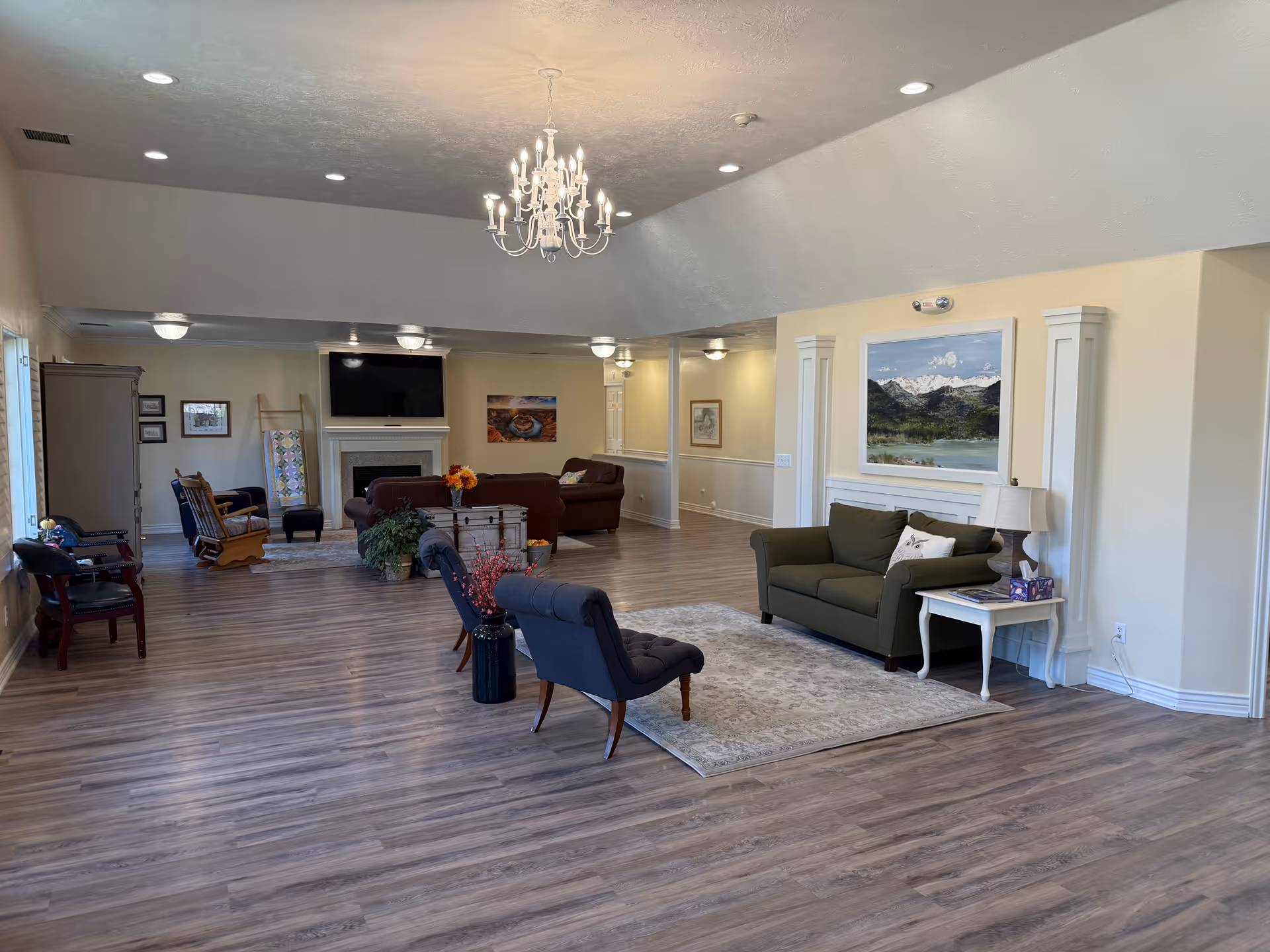 Spacious senior living lobby with a chandelier, seating area, fireplace, and artwork.