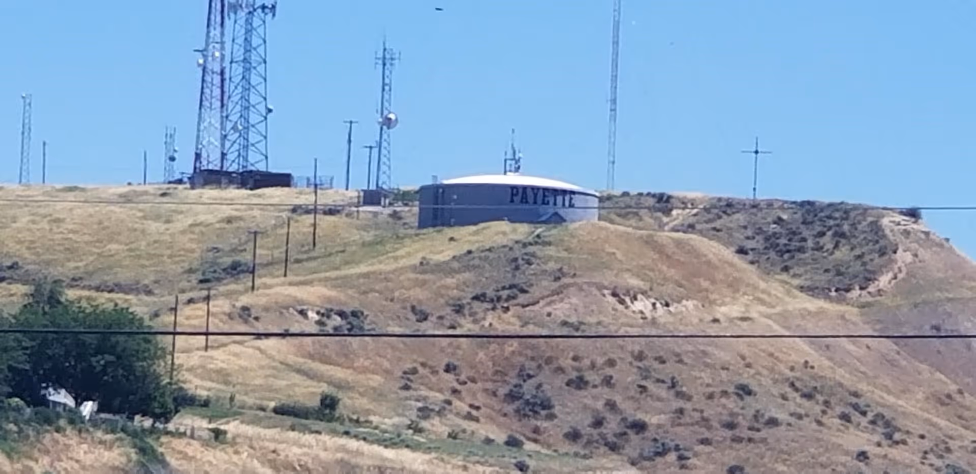 Hilly terrain with a Payette water tank and multiple communication towers.