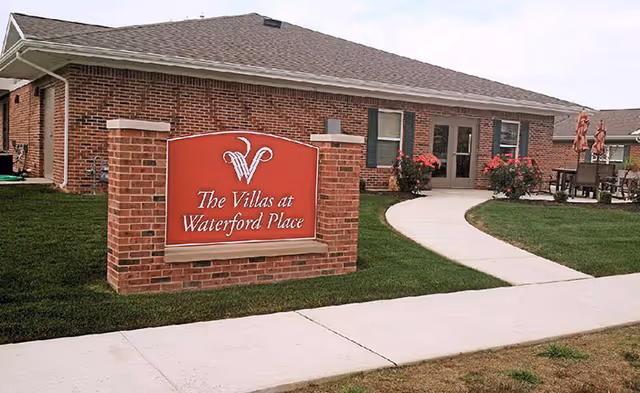 Curved walkway leads to a brick building with The Villas at Waterford Place sign.