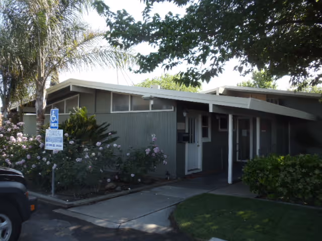 Single-story gray senior care facility exterior with handicap parking sign