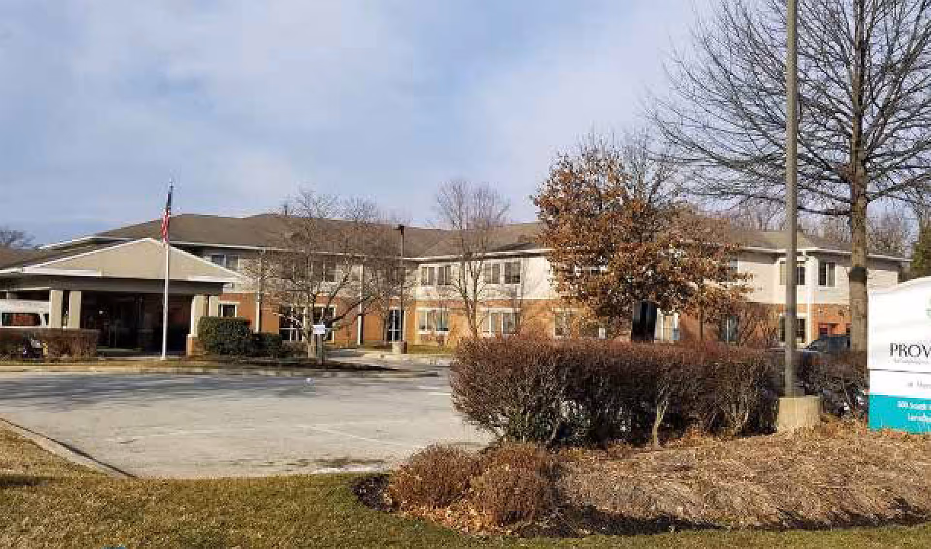 Exterior view of Providence at Mercy Fitzgerald building with entrance, flag, and parking lot.