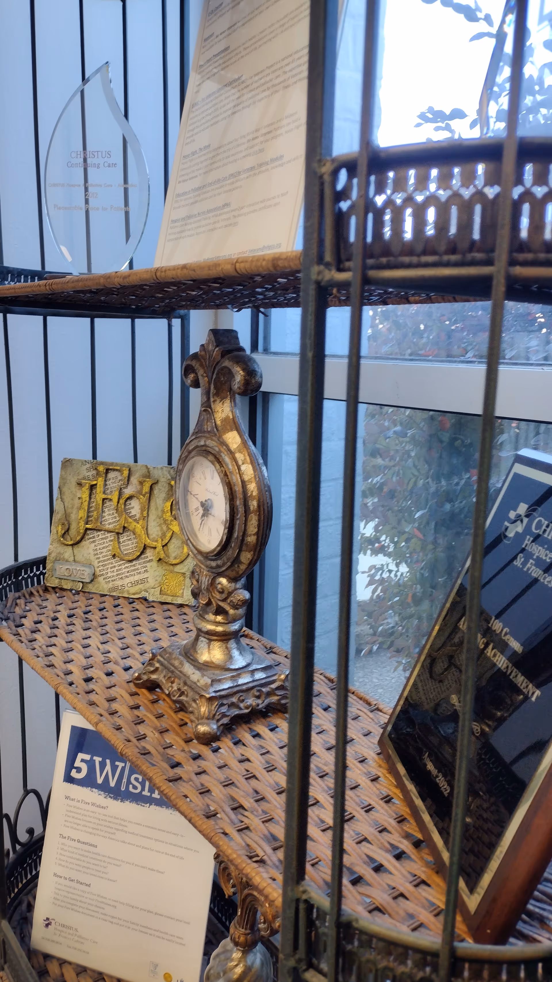 Ornate clock and decorative items on a wicker shelf beside a window.
