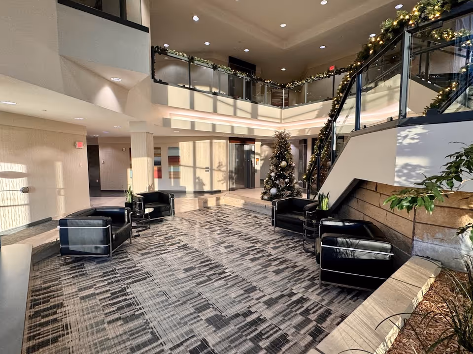 Modern senior living lobby with black leather chairs, Christmas tree, garland, and staircase.