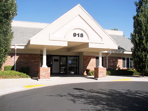 Front entrance of a brick senior care facility with a peaked white canopy, address 915.