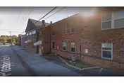 Brick building exterior of Pleasant Acres Nursing and Rehabilitation Center beside a street.
