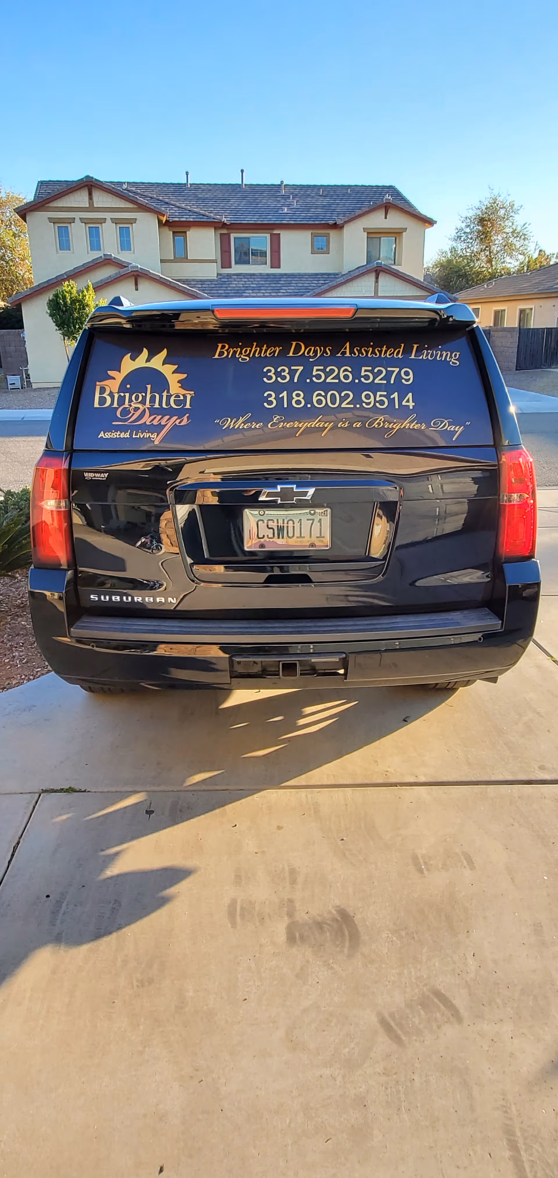 Rear view of a branded Brighter Days Assisted Living van parked near a two-story home.