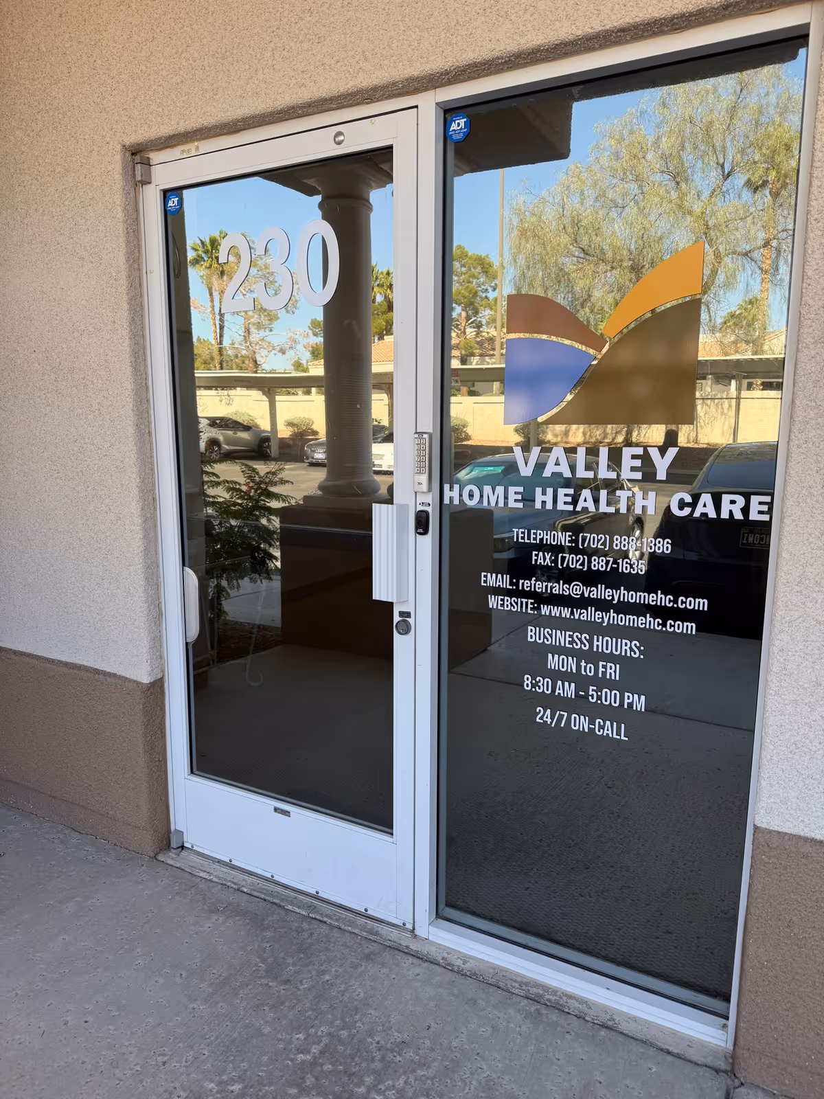 Glass entrance door with Valley Home Health Care logo and parking lot reflection outside.