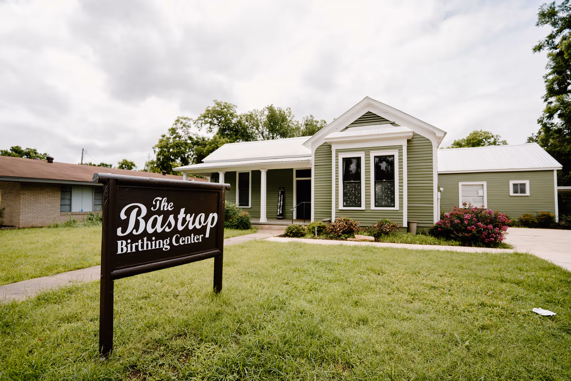 Green single-story building with white trim and a large sign reading The Bastrop Birthing Center.