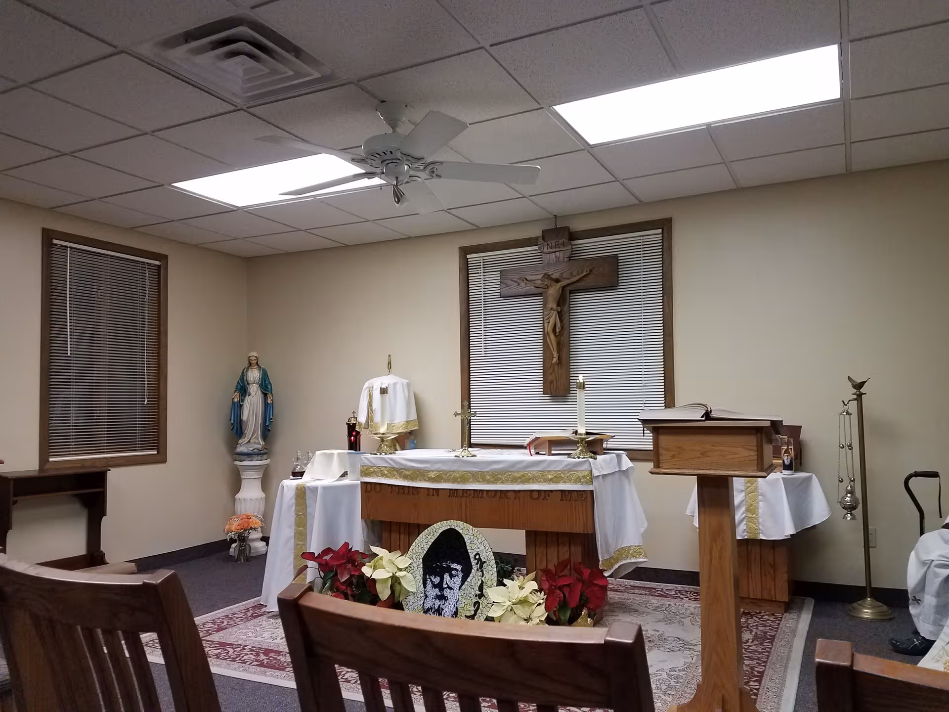Small indoor chapel in a senior facility with altar, crucifix, statue, and lectern.