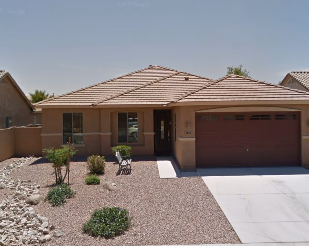 Front exterior of a single-story assisted living facility with a two-car garage and desert landscaping.