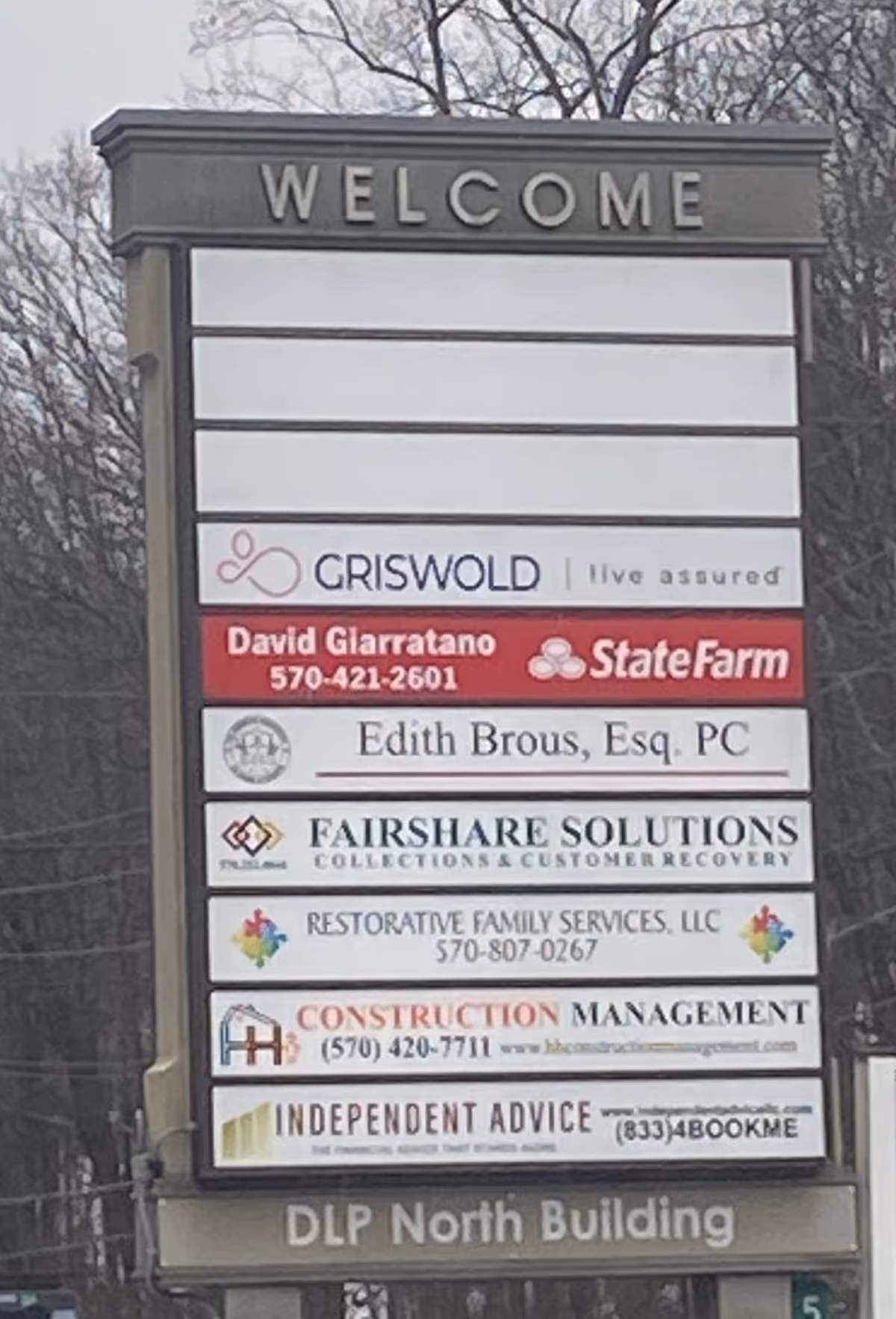 Outdoor building signboard listing tenants with a prominent WELCOME header.