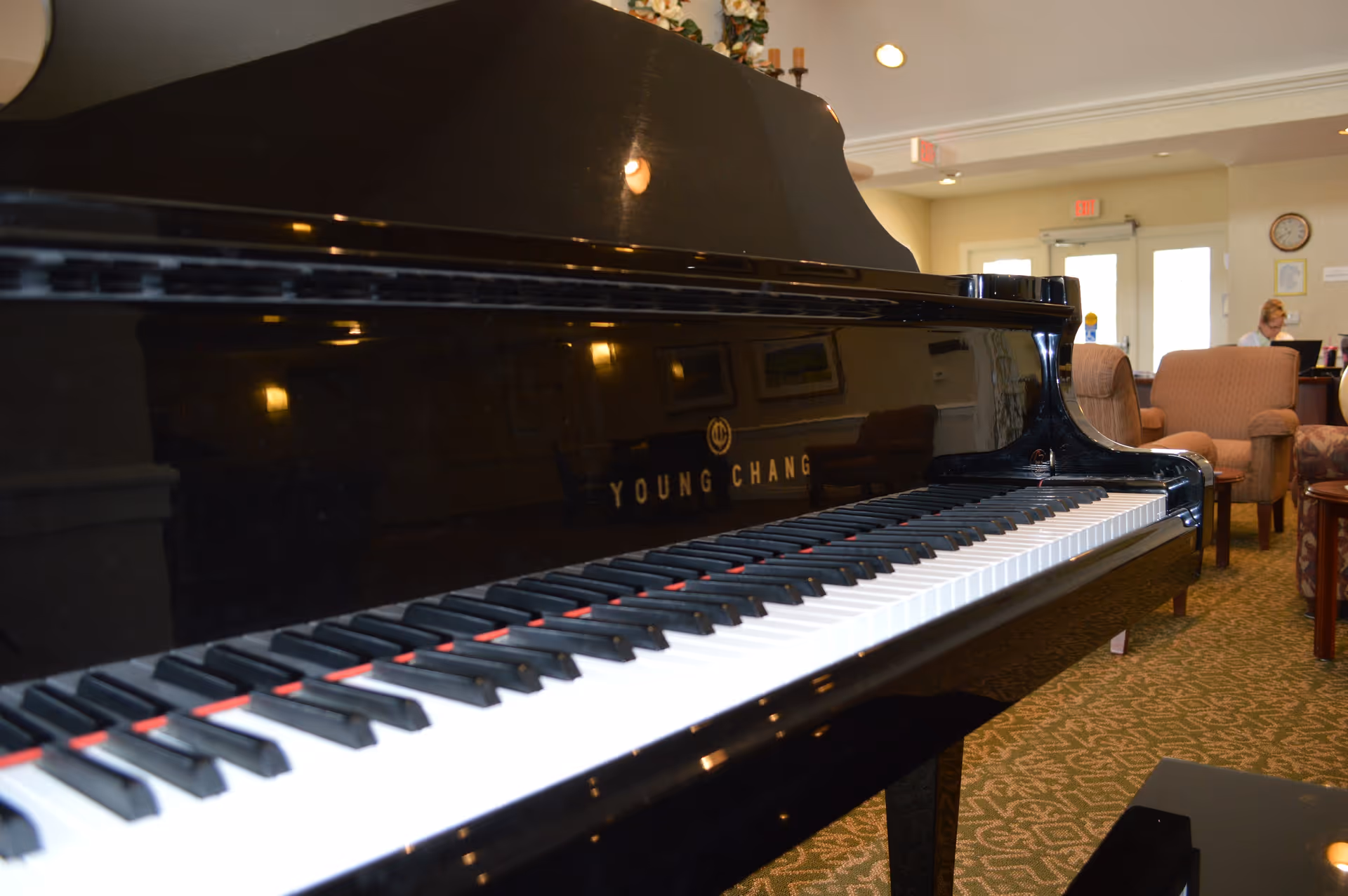 Close-up of a black grand piano in a senior living lounge.