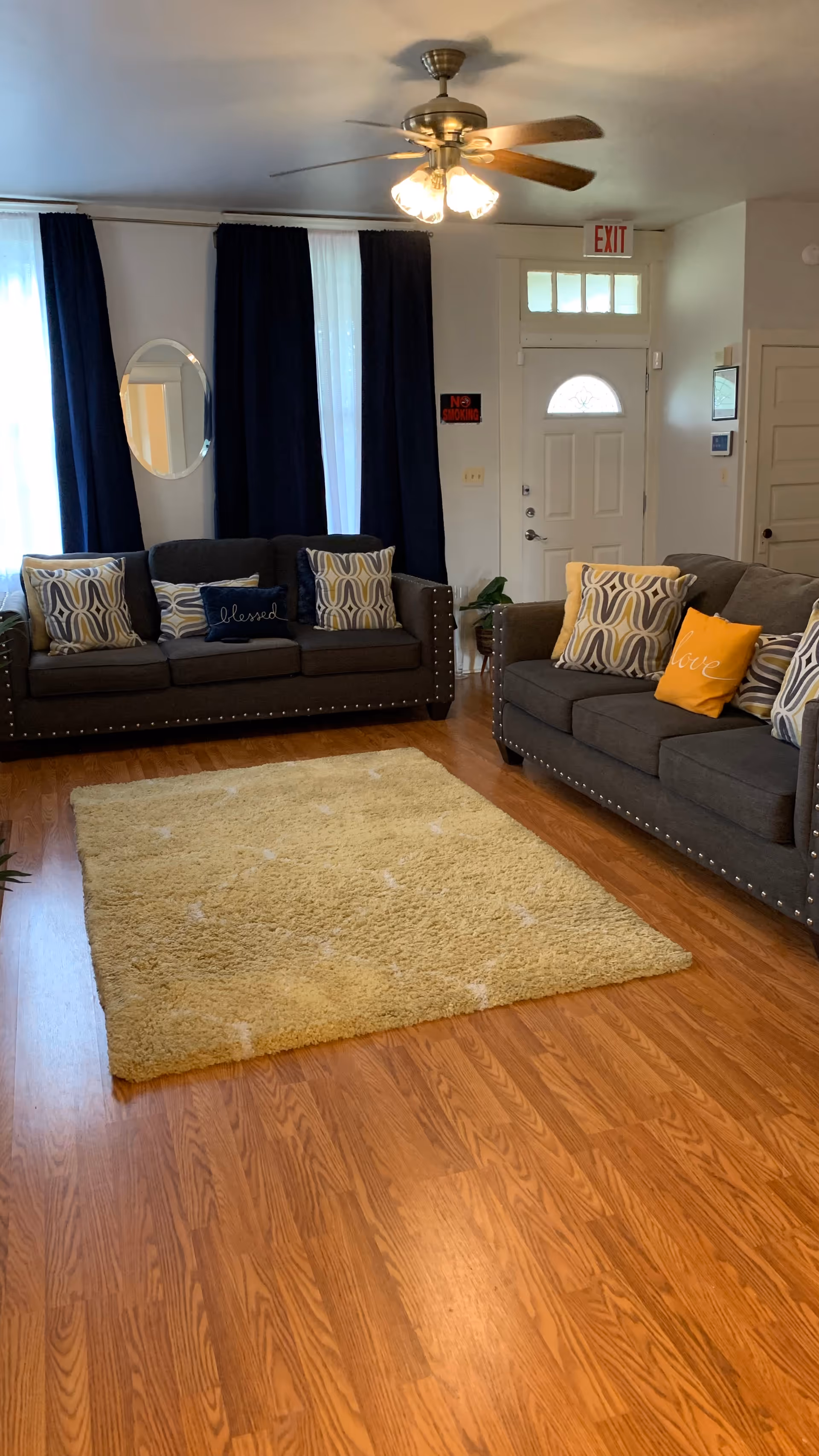Two dark gray sofas with patterned cushions in a cozy living room with a beige rug.