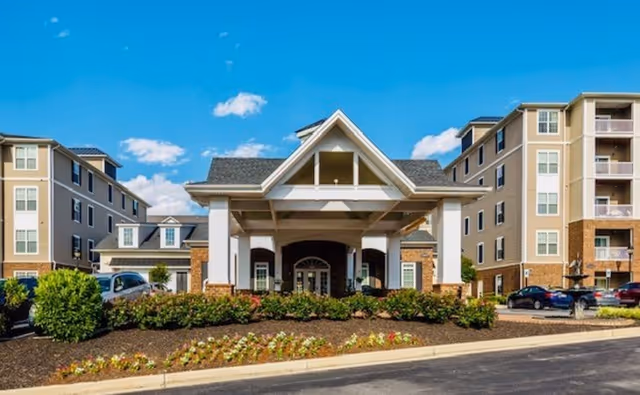 Front view of Regency Crest senior living facility with a landscaped entrance and parked cars.