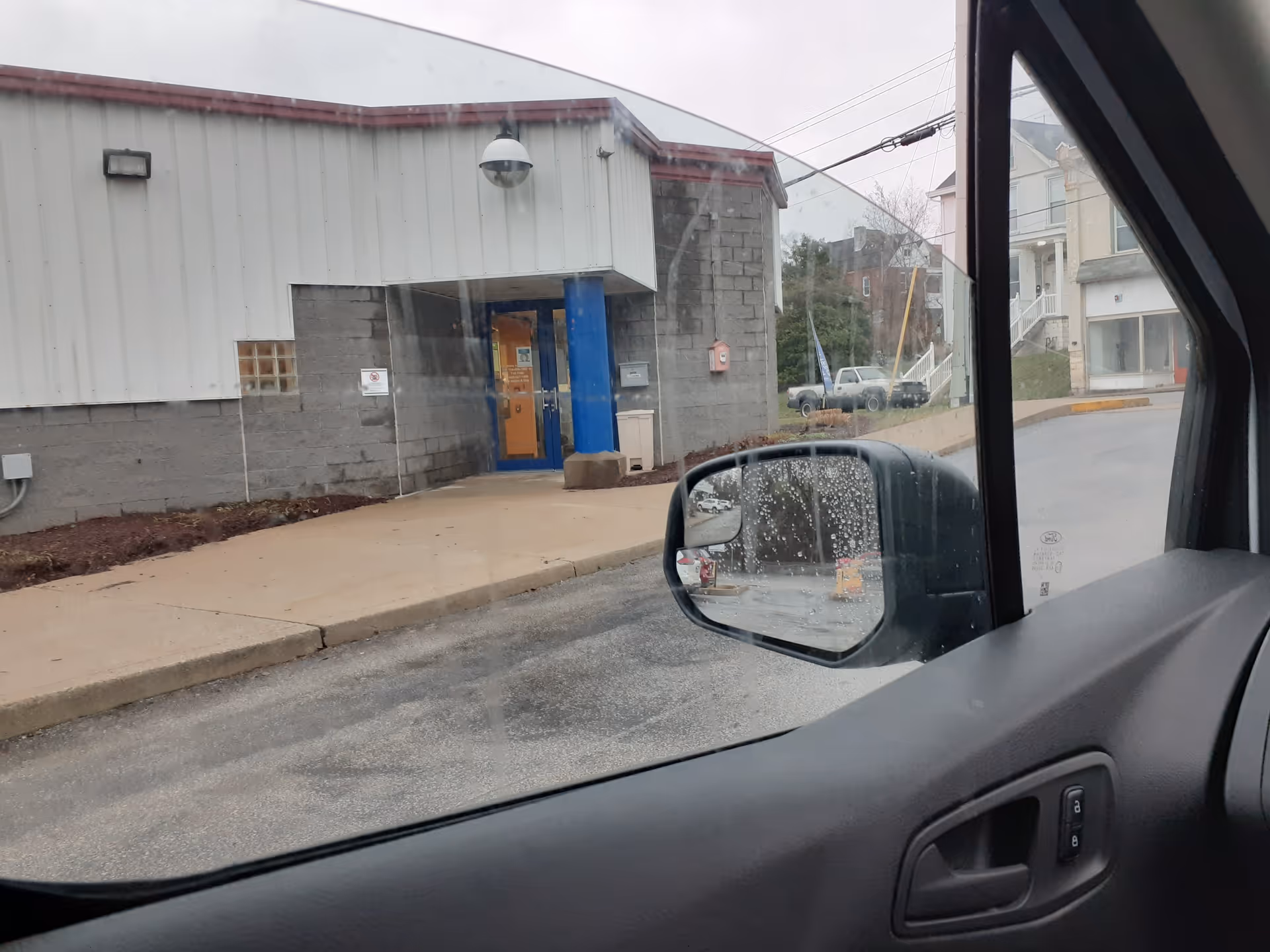 View from inside a vehicle of a building exterior with a blue entrance door