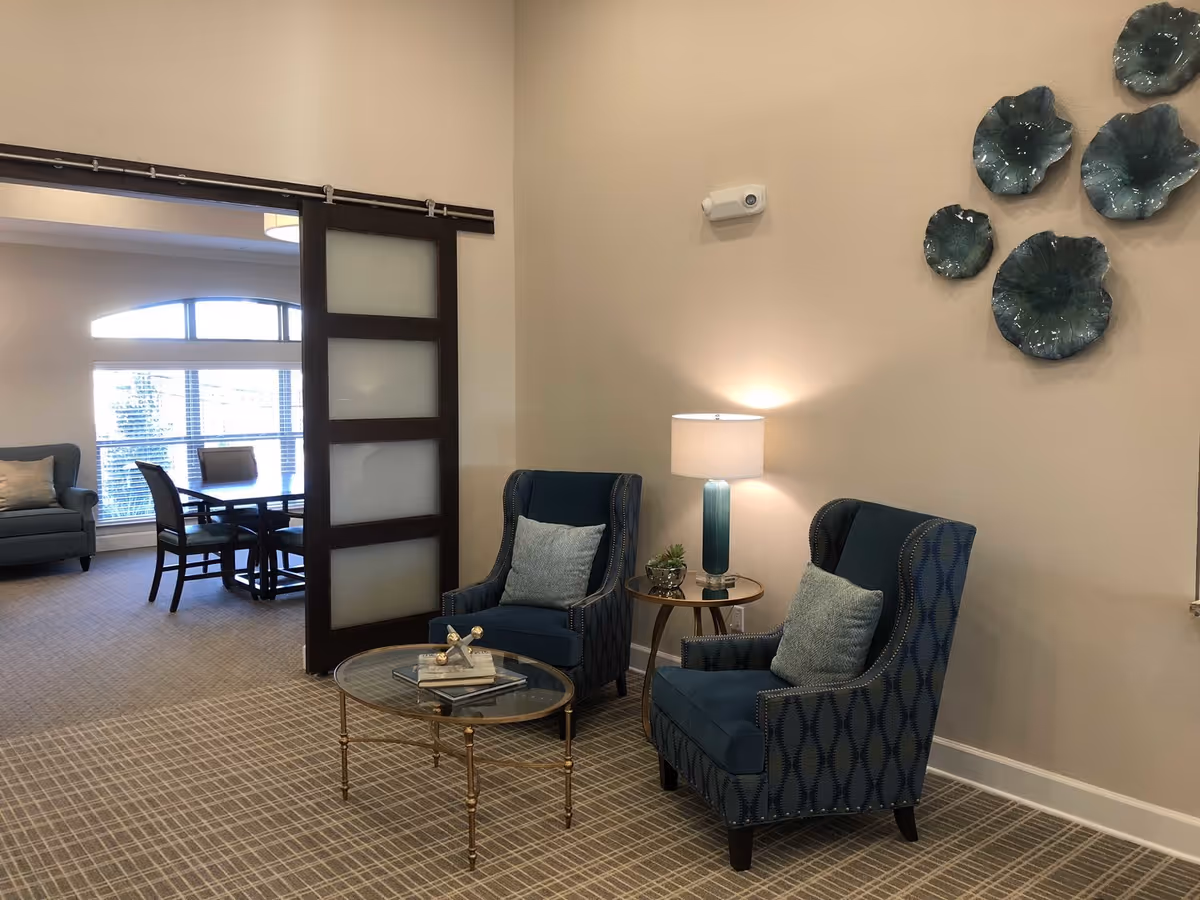 Two blue patterned armchairs with a glass coffee table in a cozy lounge area.