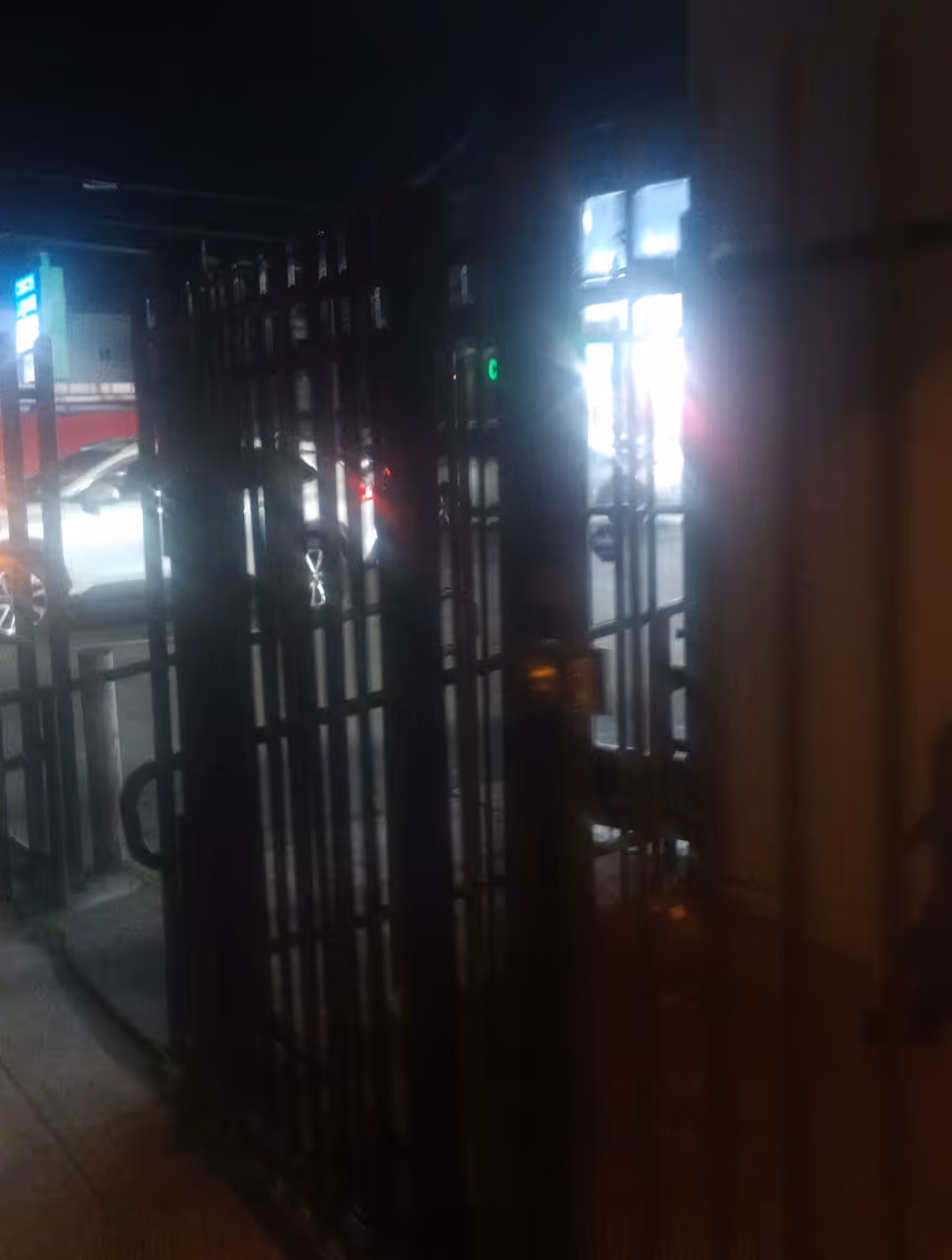 Dark exterior entrance with metal gates and bright street lights.