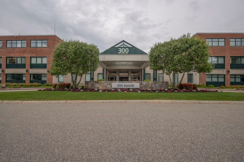 Exterior view of a brick senior living facility with a central entrance and landscaping.