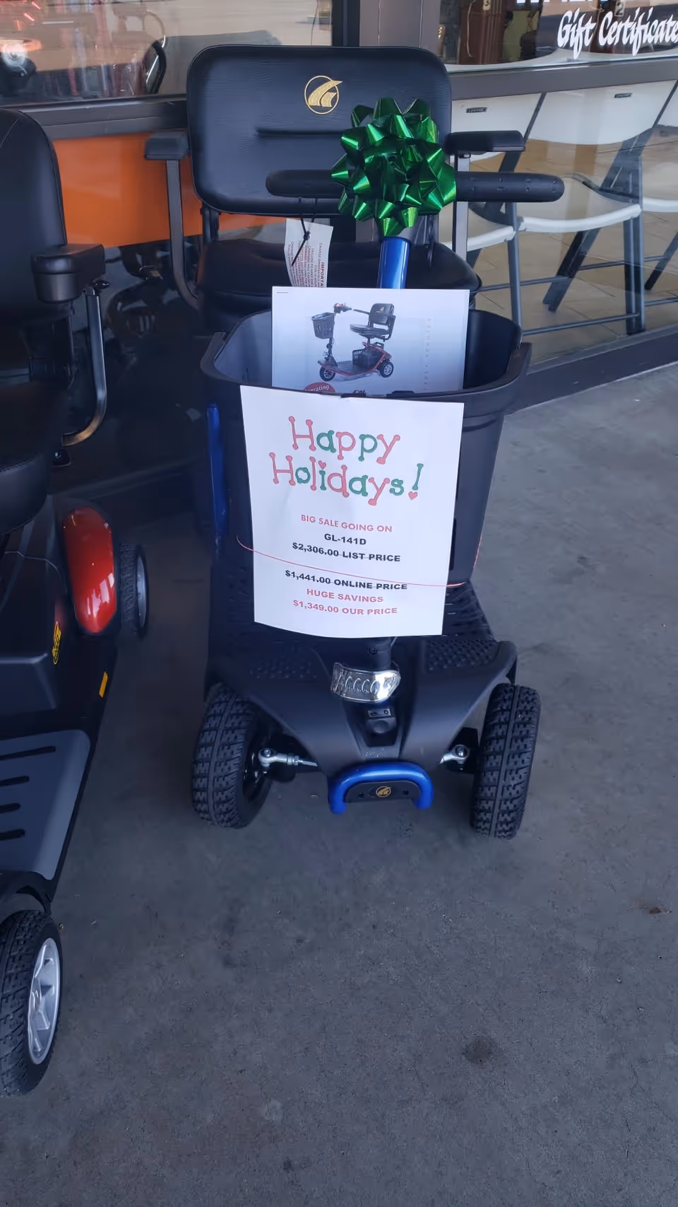 Mobility scooter with green bow displayed outside storefront during holidays