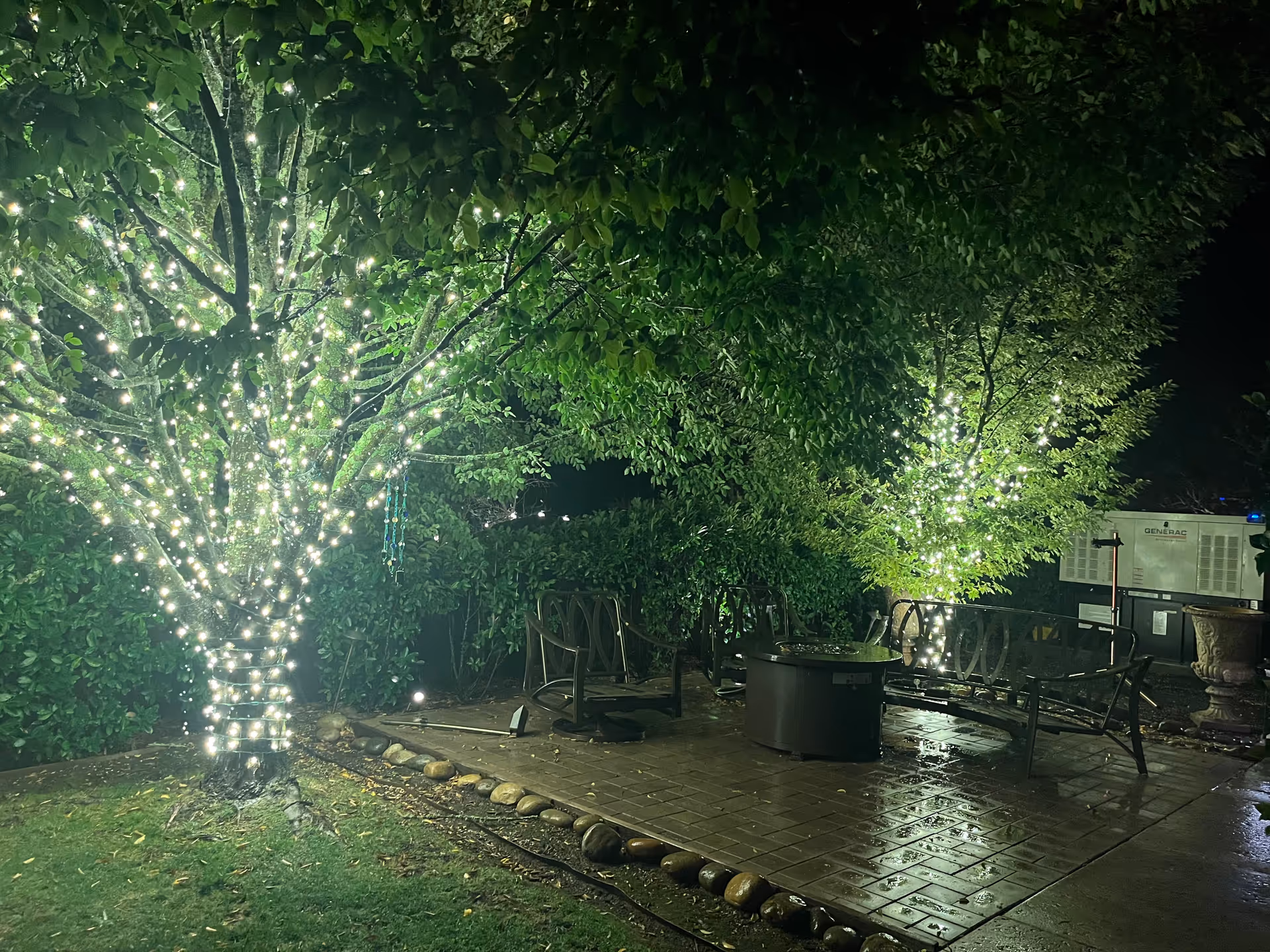 Outdoor patio at night with illuminated trees and seating.