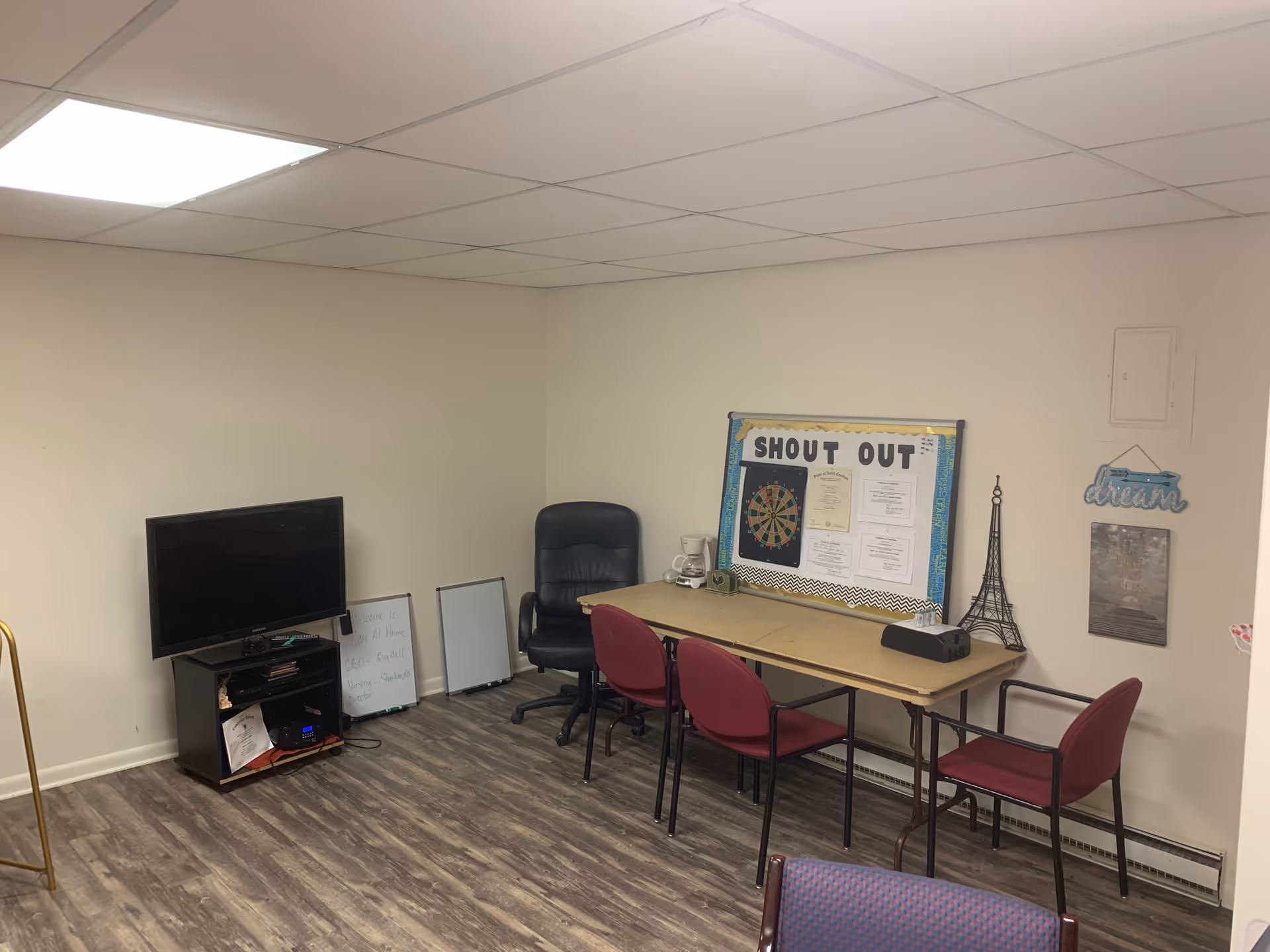 Small activity room with a long table, chairs, TV, and bulletin board.