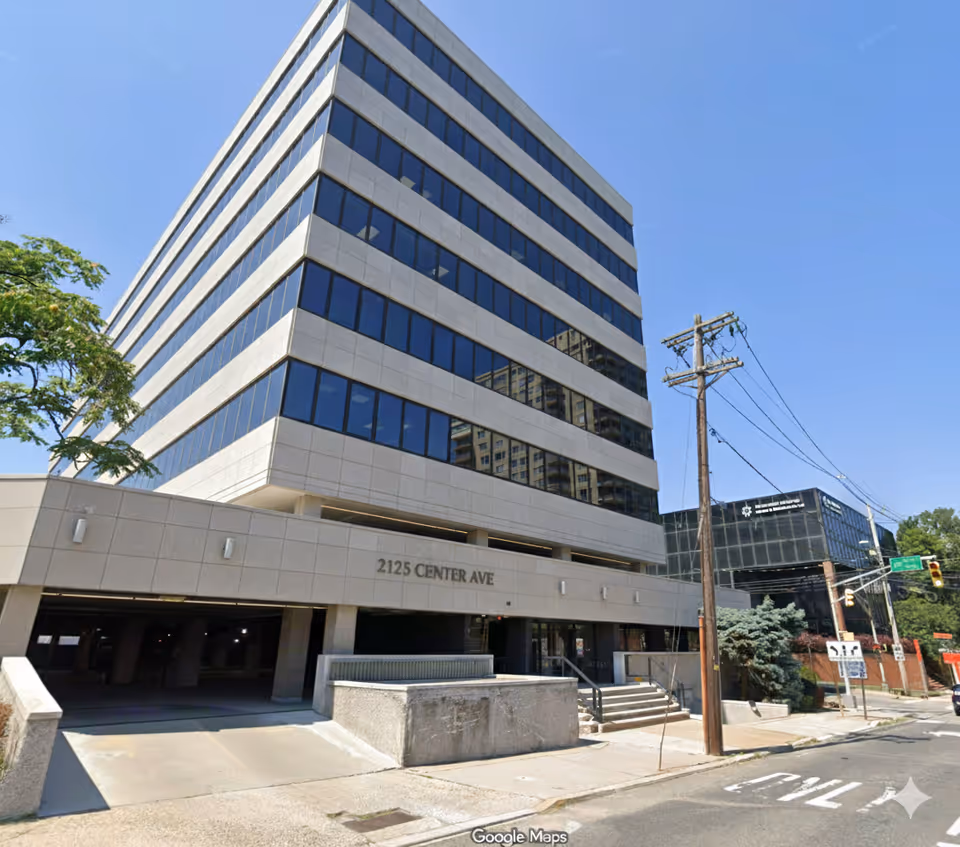 Tall modern building with glass windows along Center Ave under a clear blue sky.
