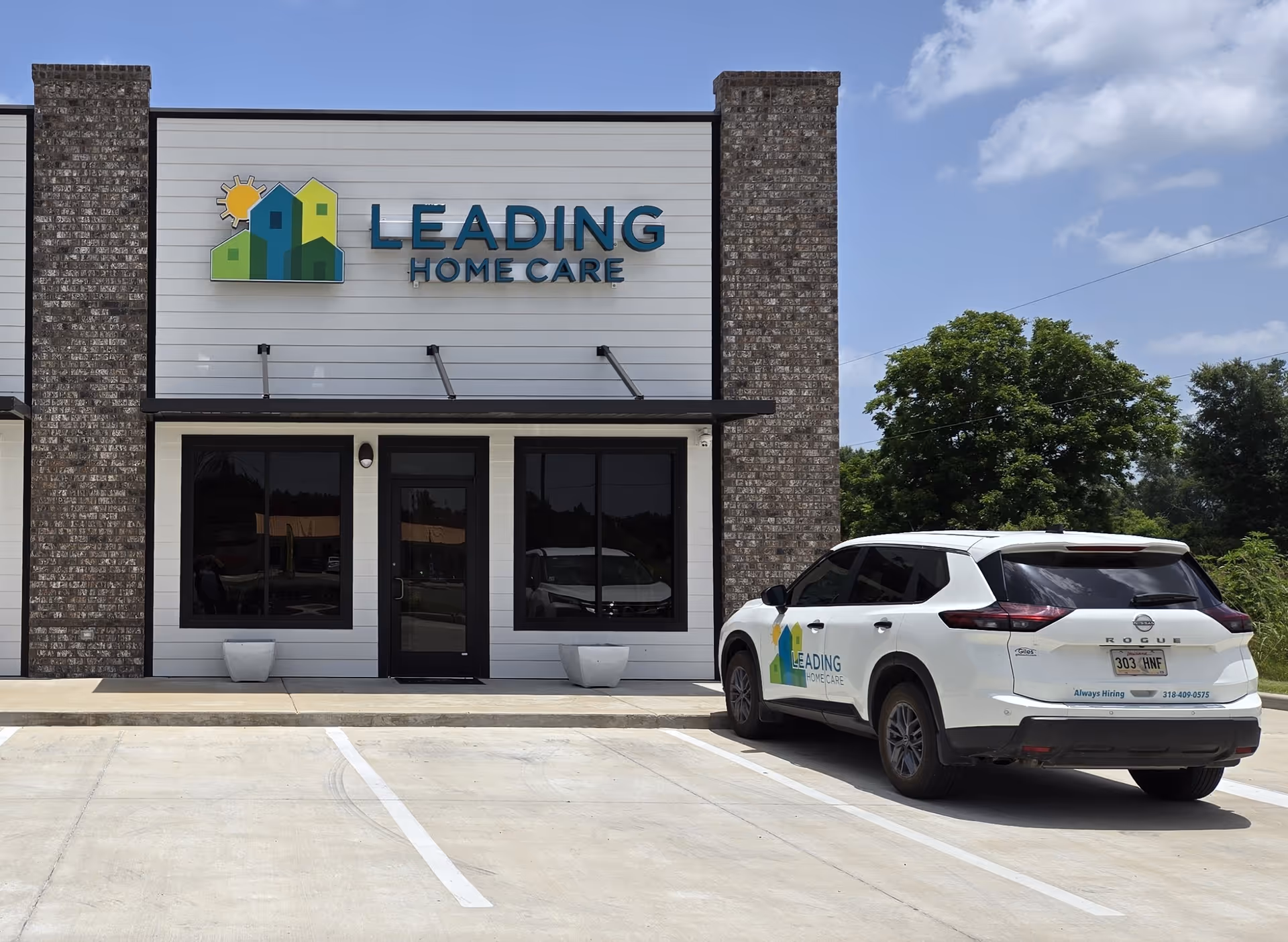 Exterior of Leading Home Care building with logo signage and a parked SUV.