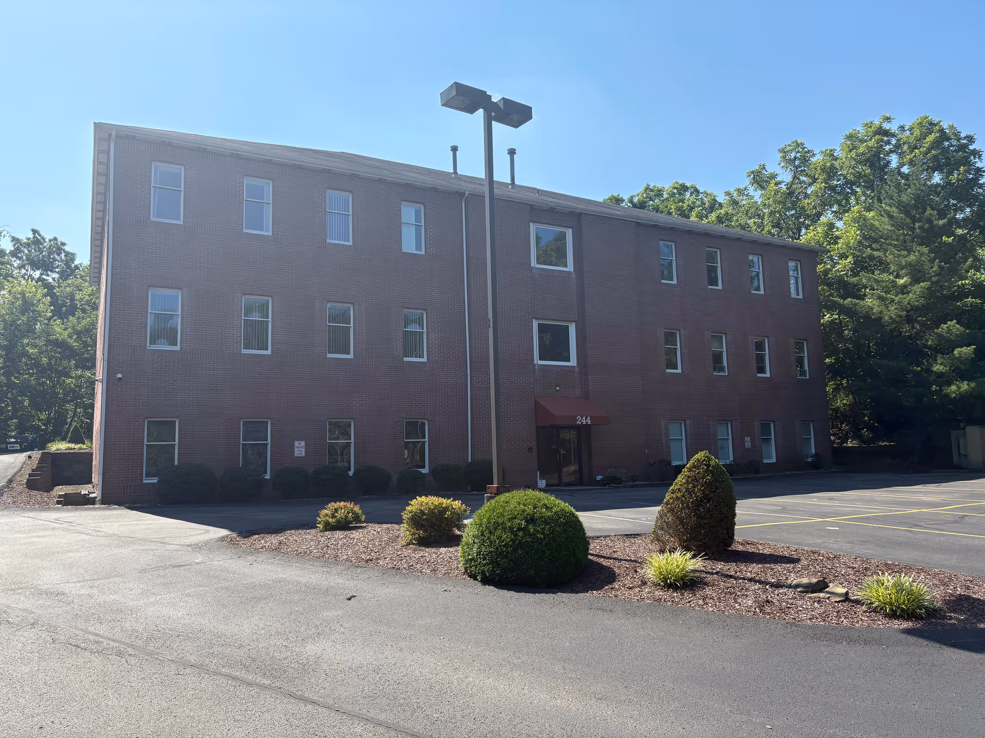 Three-story brick Avondale Care Group of Pennsylvania facility with front entrance, parking lot, and surrounding shrubs.