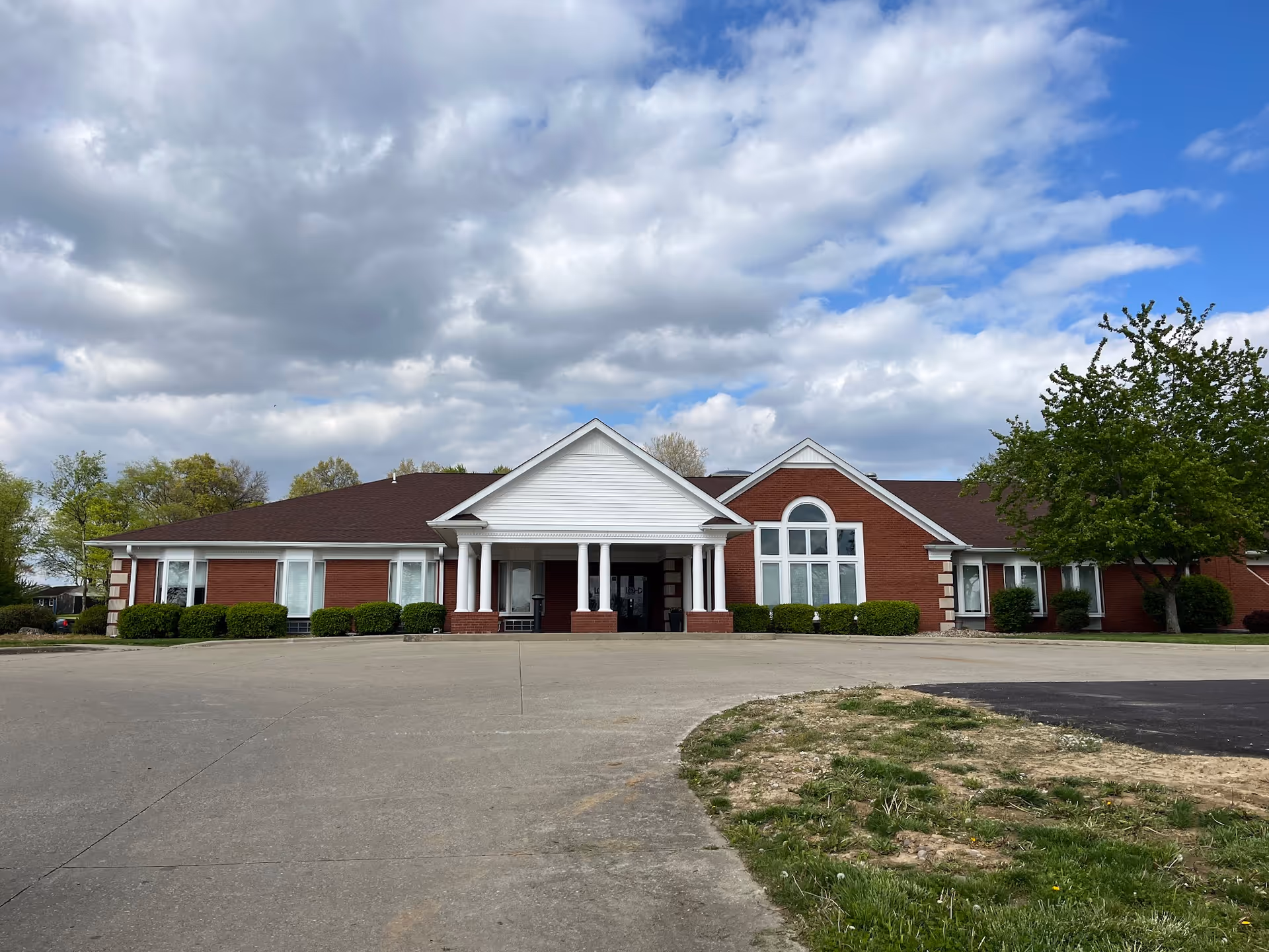 Exterior view of a red brick facility with white columns and a central entrance.