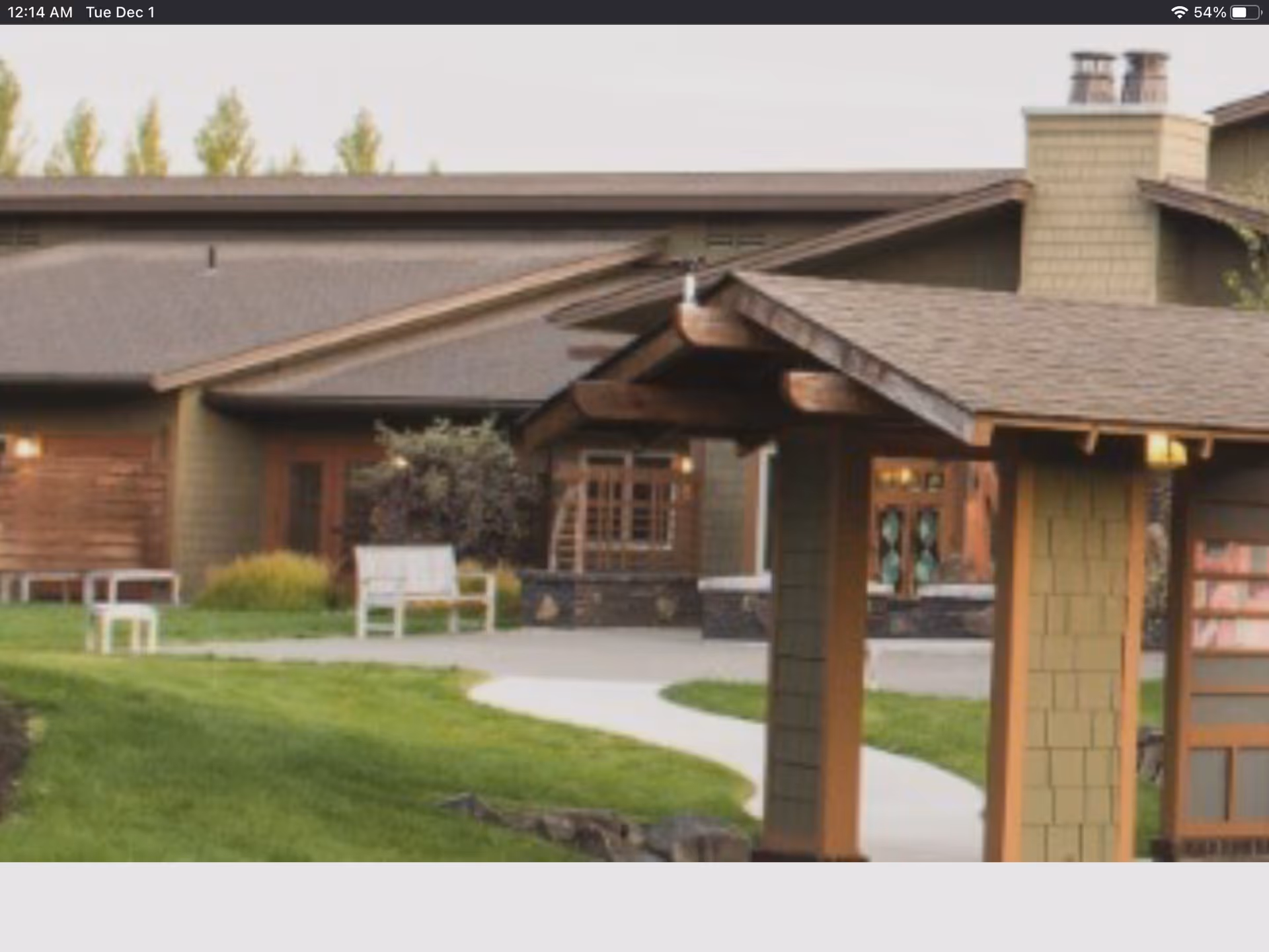 Front exterior of a senior living facility with walkway, green lawn, and entrance.