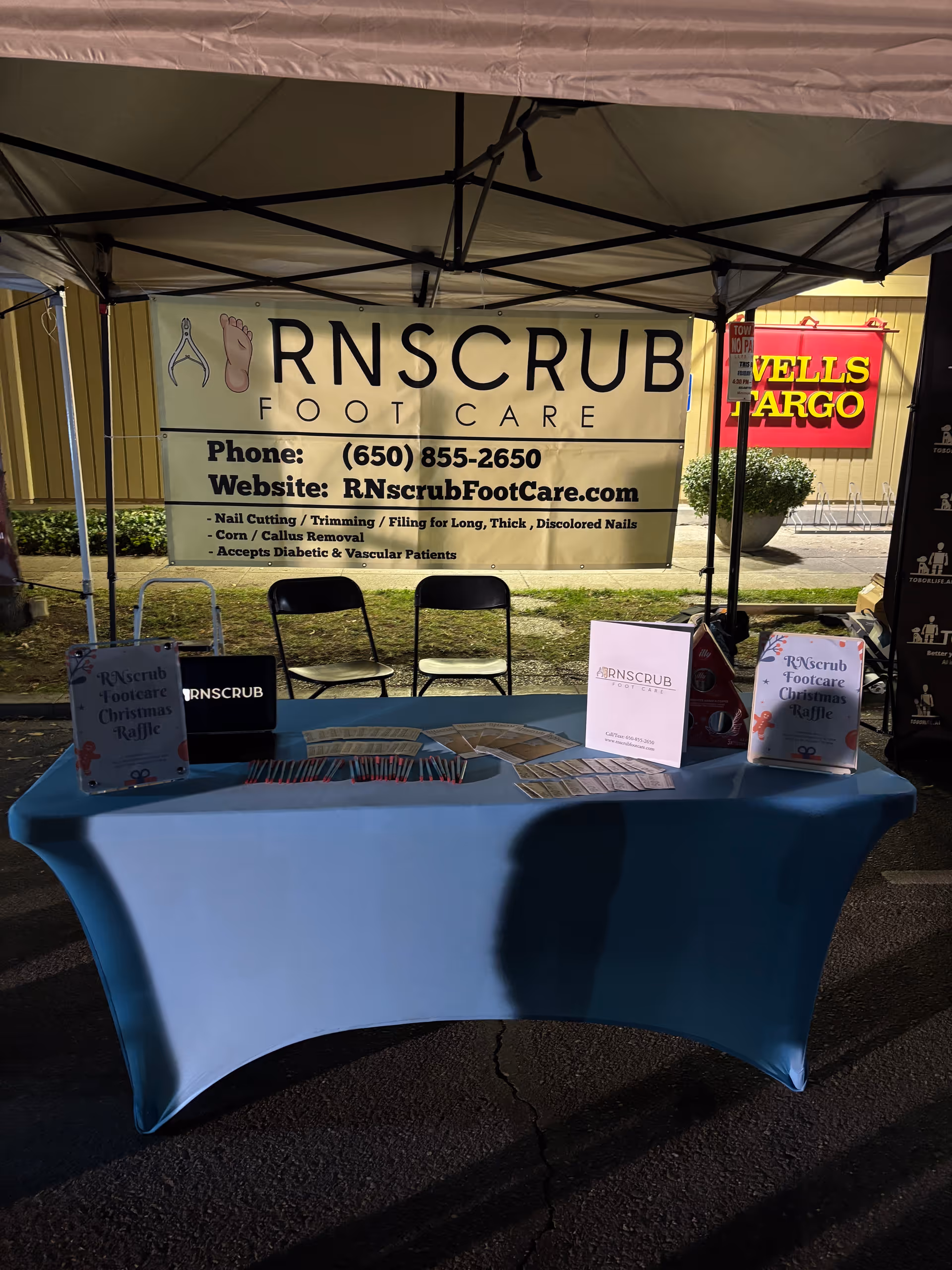 Outdoor tent booth for RNscrub Foot Care with banner and blue tablecloth.