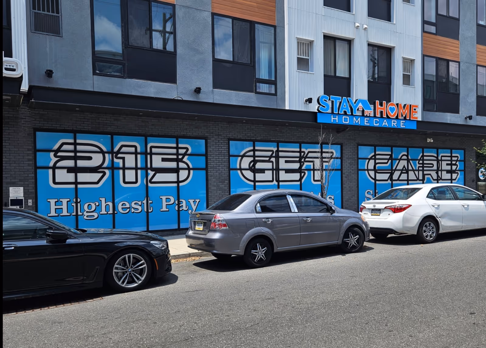 Street view of Stay at Home Homecare storefront with blue signage and parked cars.
