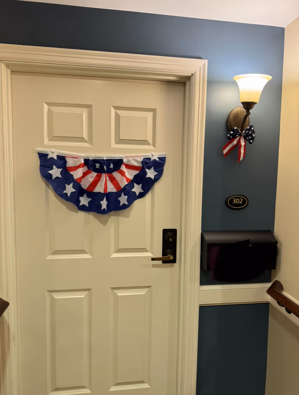 Interior hallway at a senior living facility featuring patriotic bunting on a door.