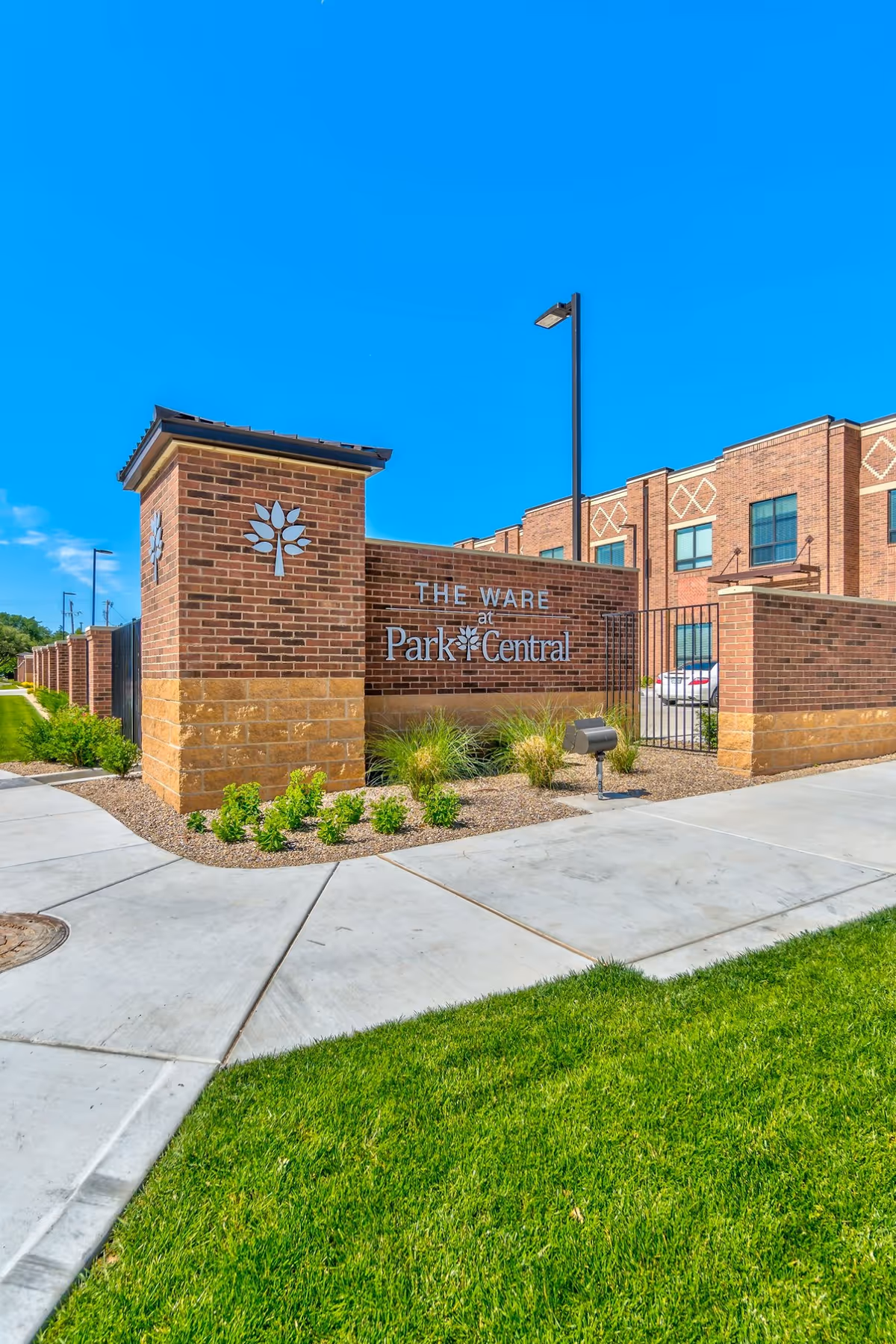 Brick building exterior with a sign reading The Ware at Park Central and landscaping.
