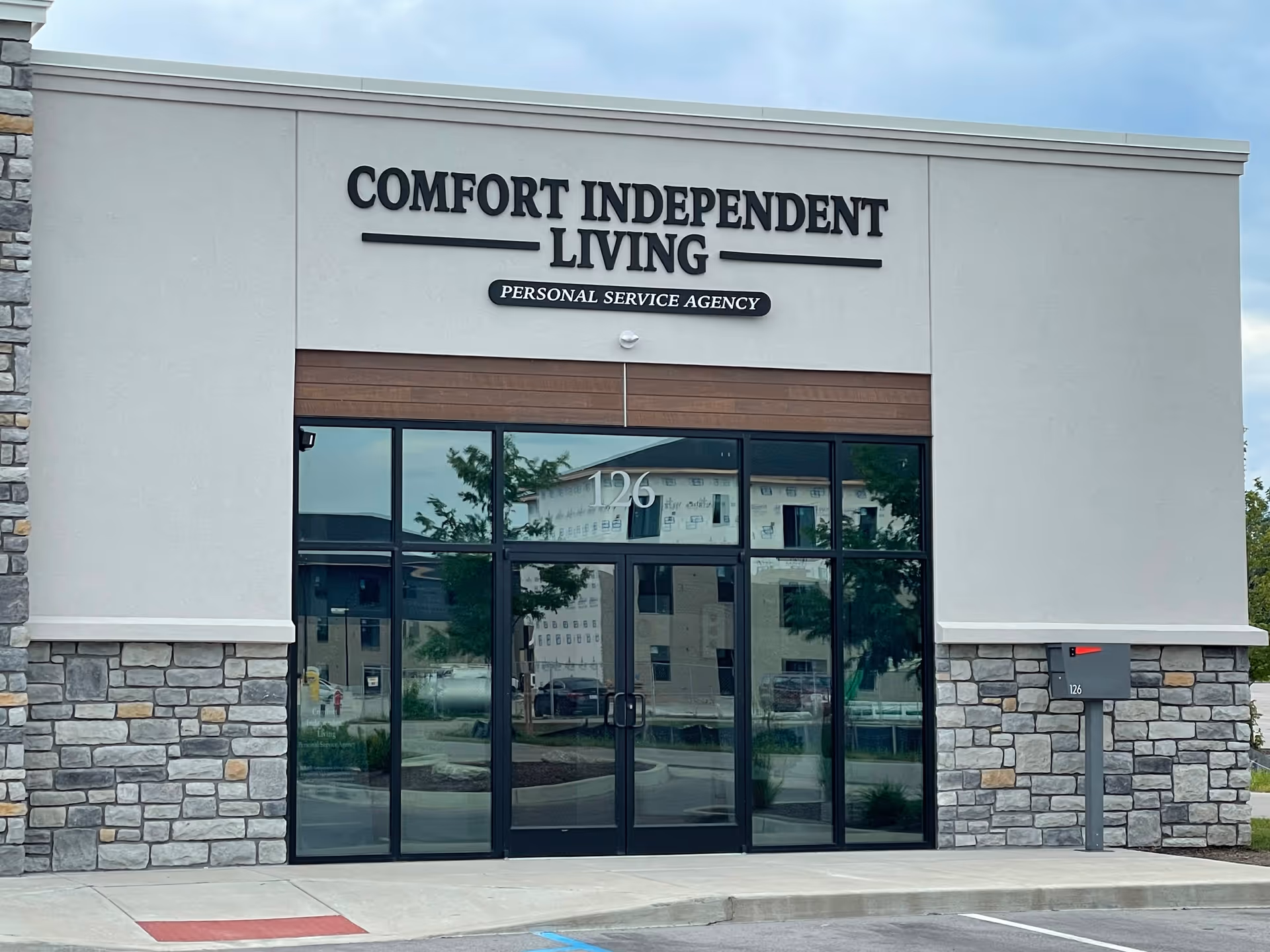 Front entrance of Comfort Independent Living facility with glass doors and stone facade.