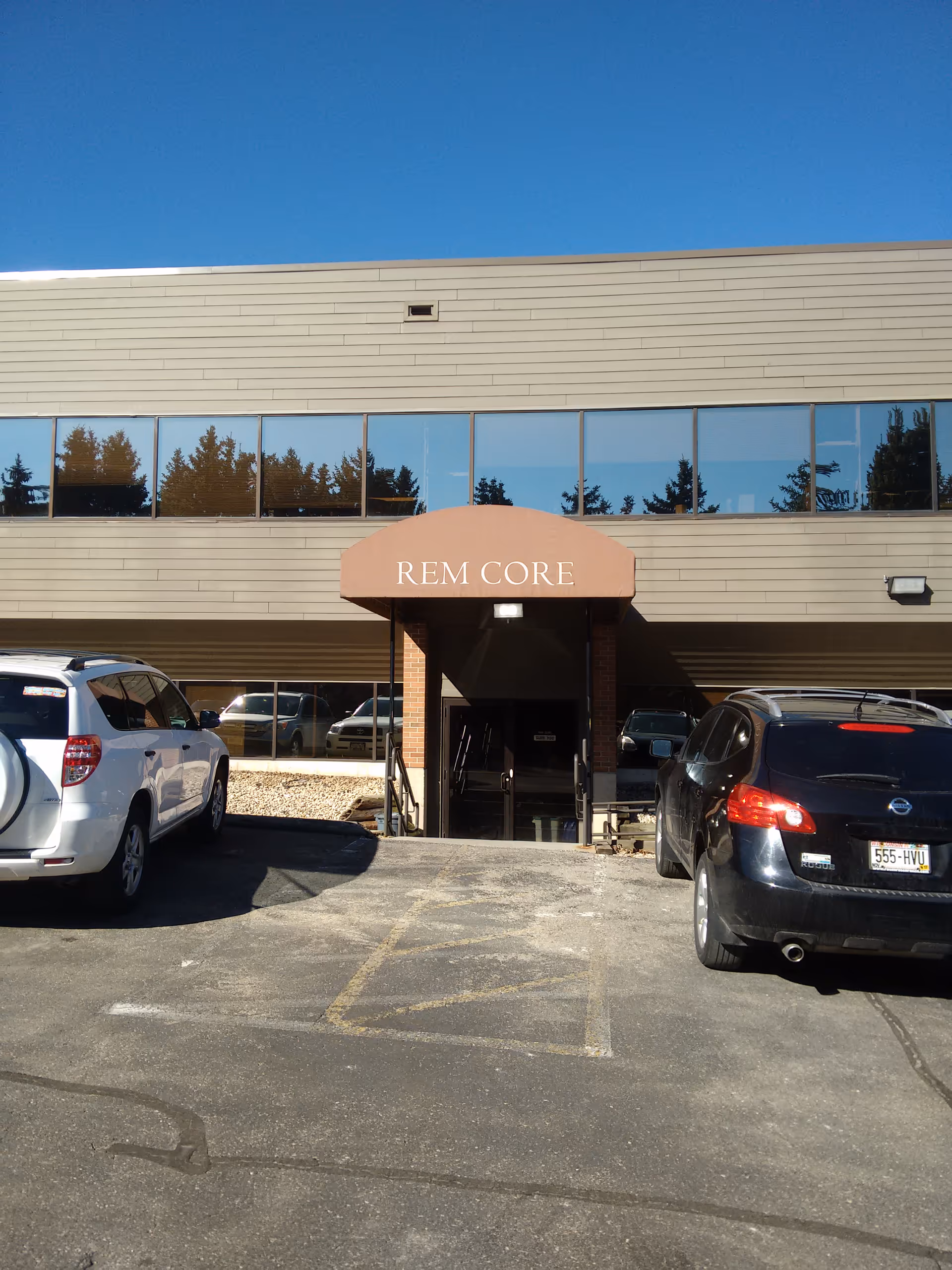 Exterior view of REM Core entrance with cars parked in front.