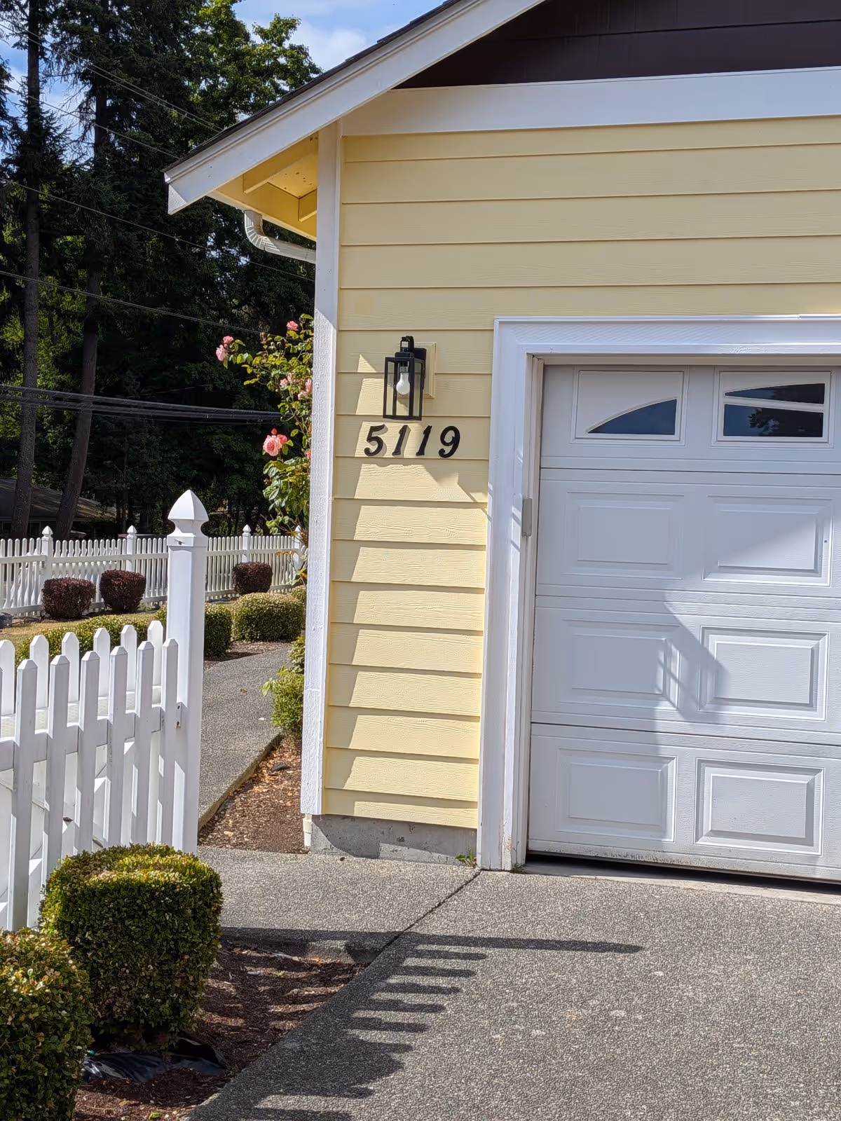 Yellow exterior of Edmonds Villa Adult Family Home with address 5119 and white garage door.