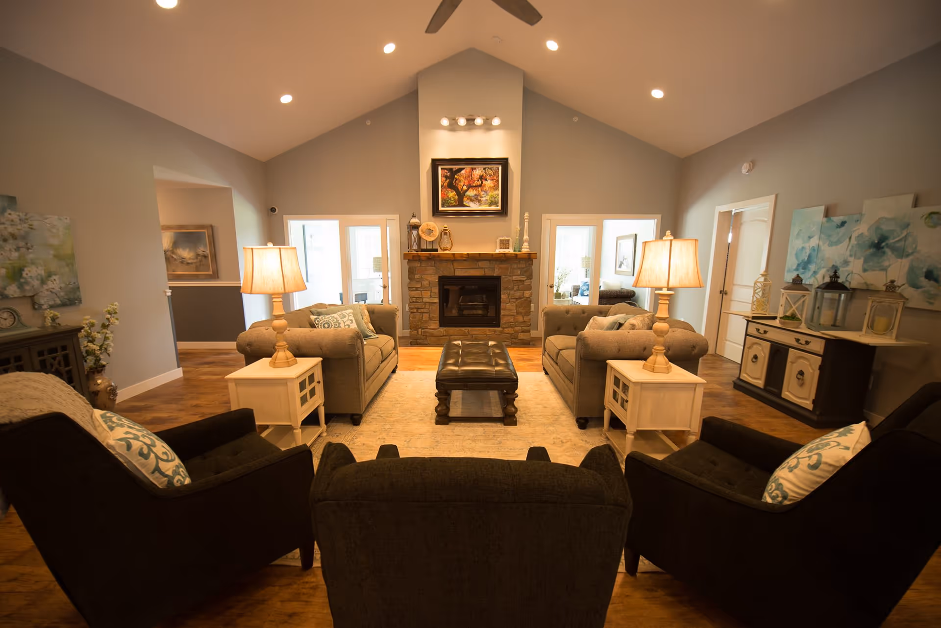 Cozy senior living lounge with a stone fireplace, sofas, lamps, and an ottoman.