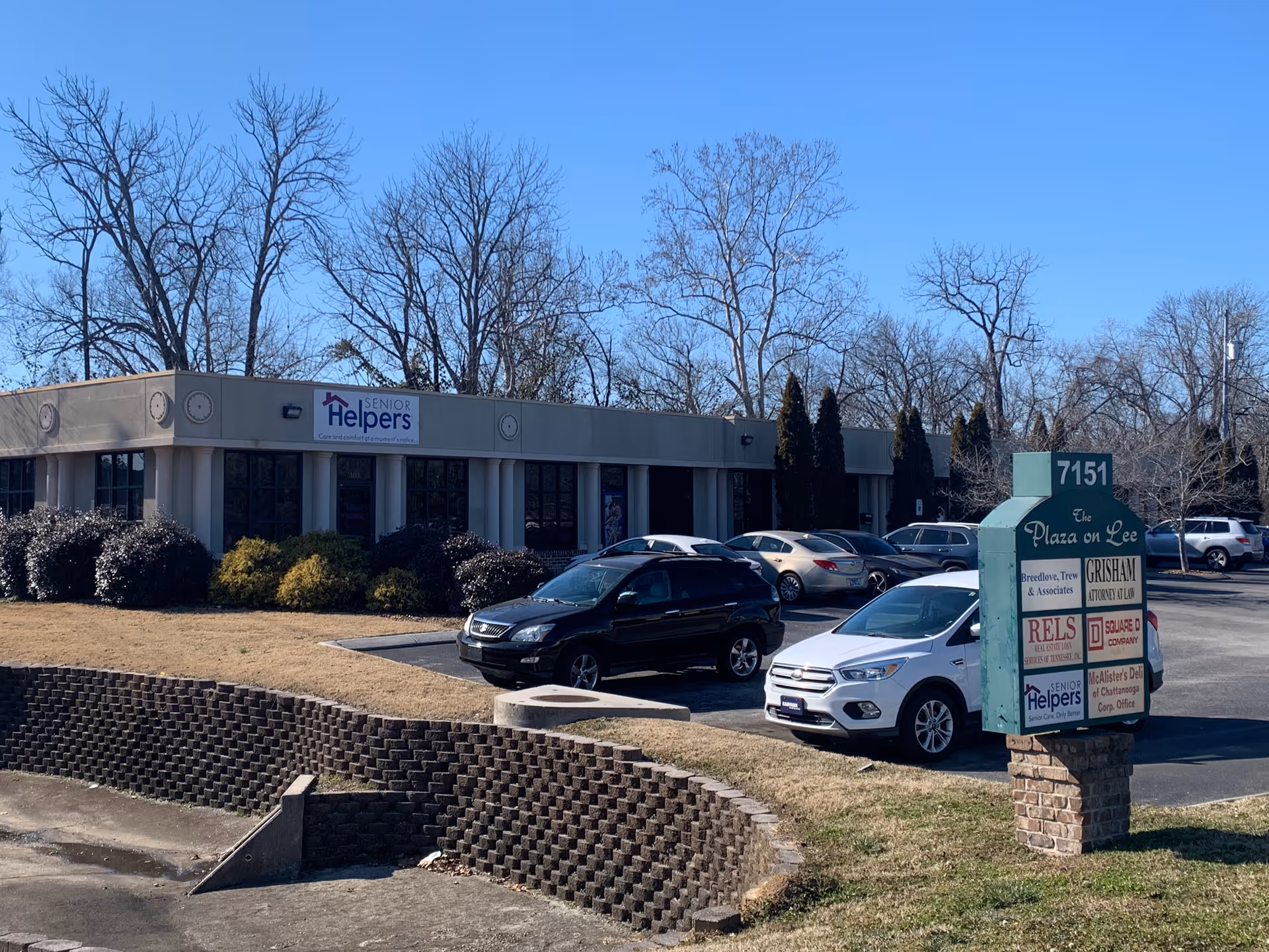 Front view of a single-story Senior Helpers building with a parking lot and sign.