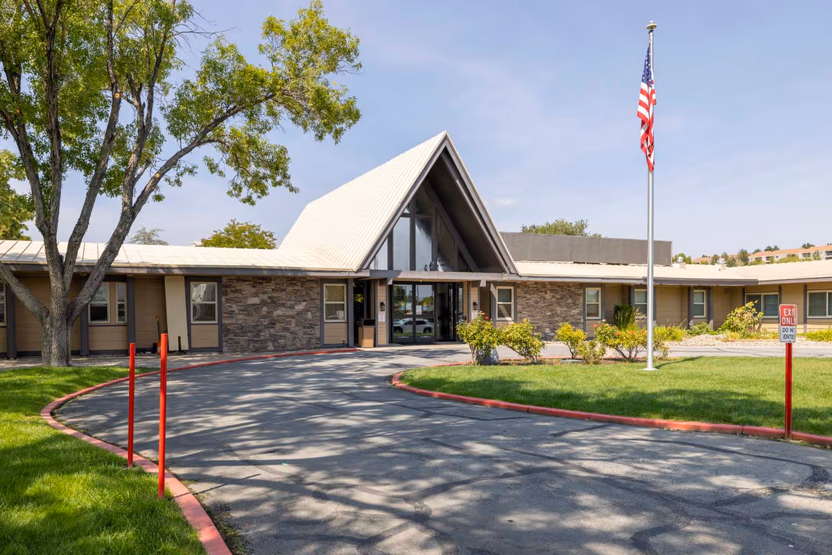 Exterior view of Rosewood Rehabilitation Center with front entrance, driveway, and flagpole.
