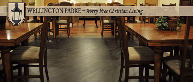 Indoor dining room with wooden tables and chairs, featuring a Wellington Parke banner.
