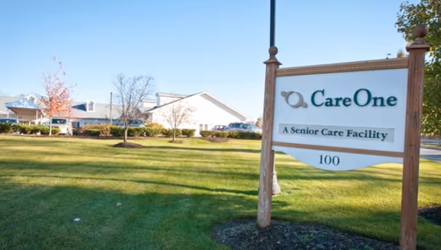 Exterior view of CareOne at Parsippany Assisted Living with sign and lawn.