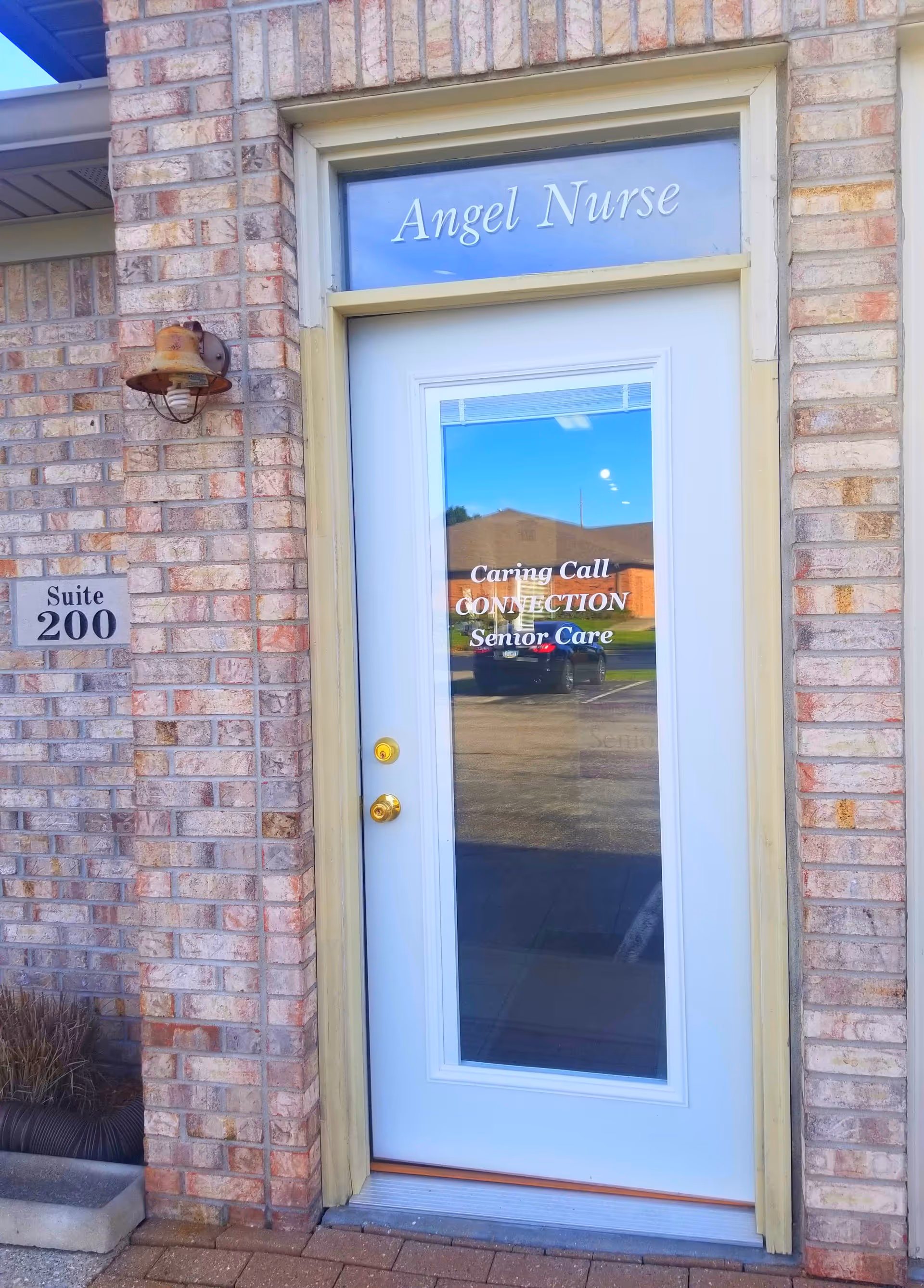 Exterior brick doorway with Angel Nurse sign on glass door and Suite 200 plaque.