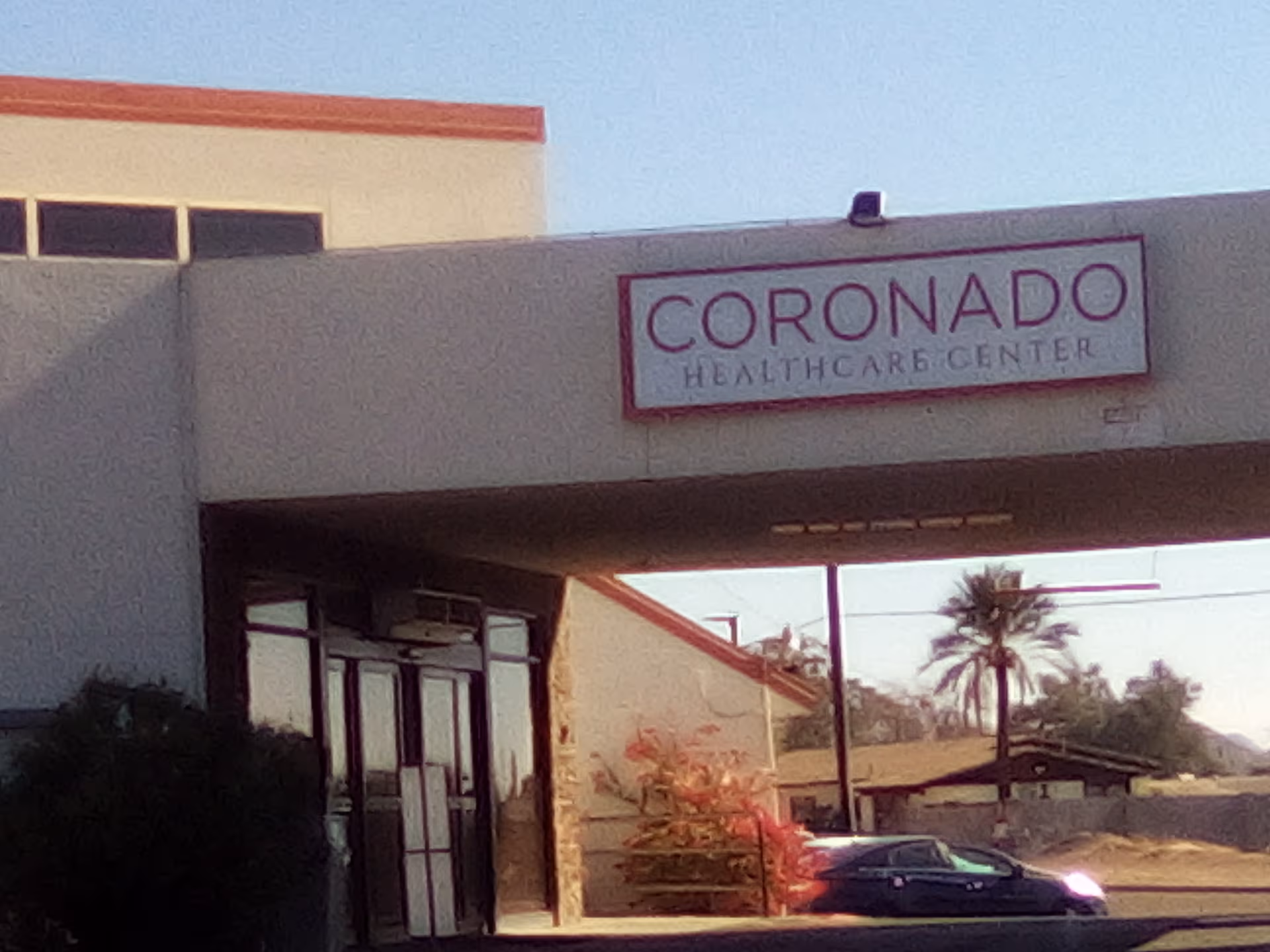 Entrance to Coronado Healthcare Center with sign on a beige building.