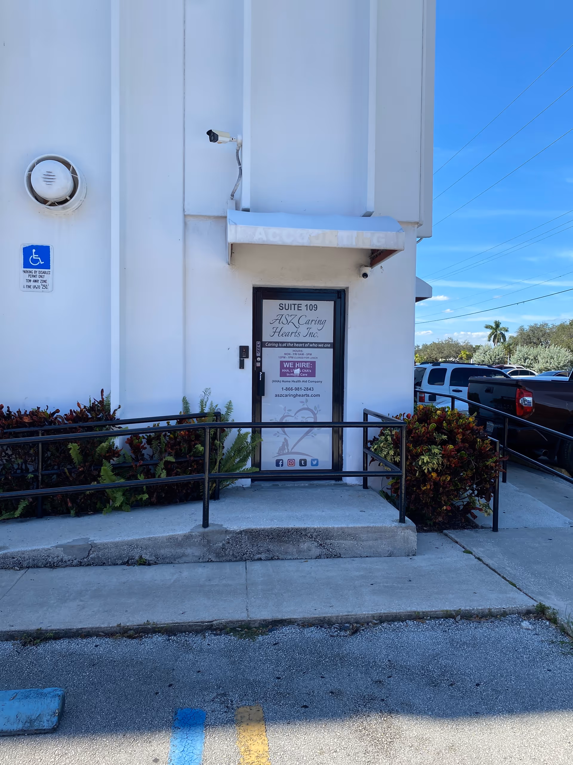 Exterior view of ASZ Caring Hearts Inc. entrance with wheelchair ramp and handicap sign.